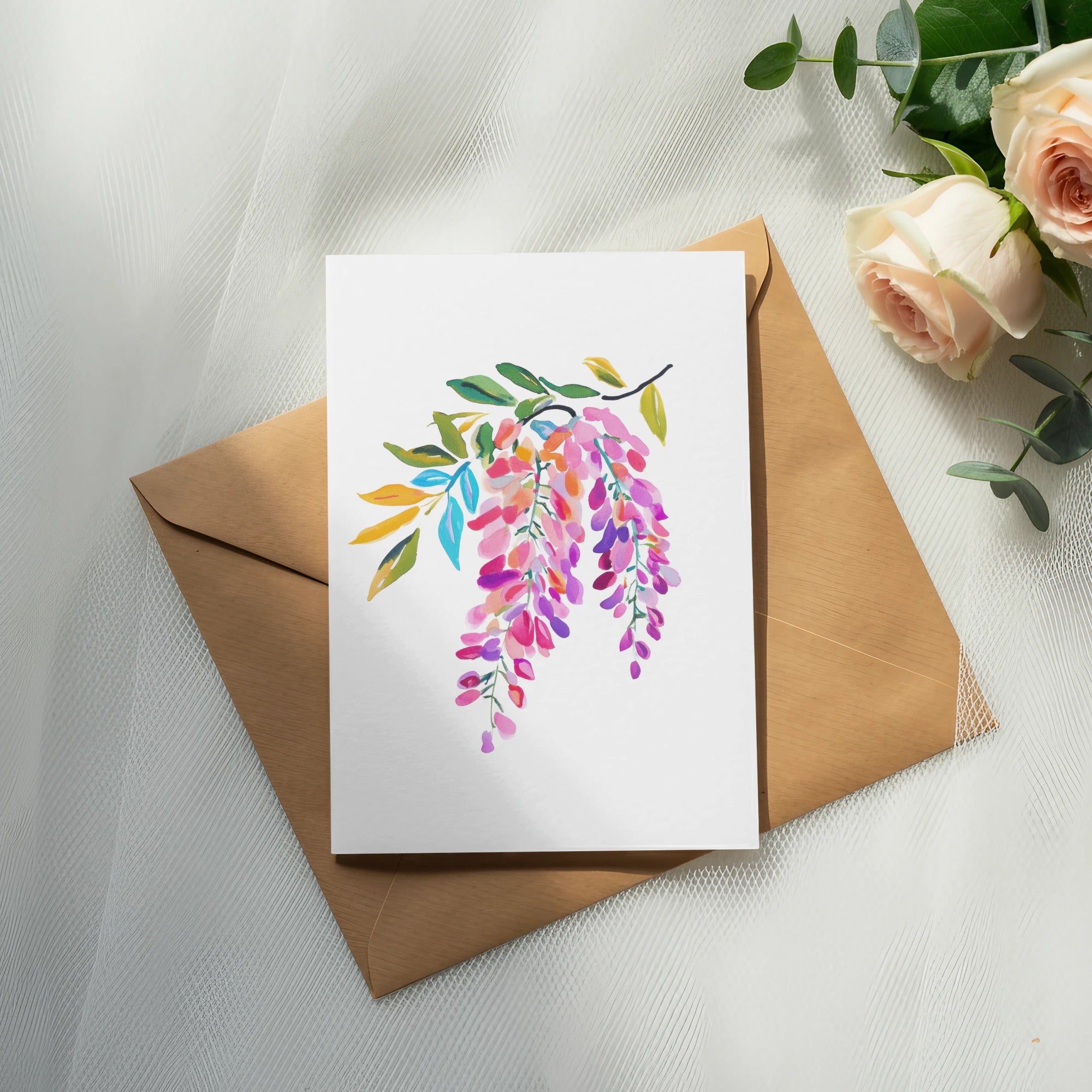 Watercolor wisteria flowers on card placed on envelope with roses.