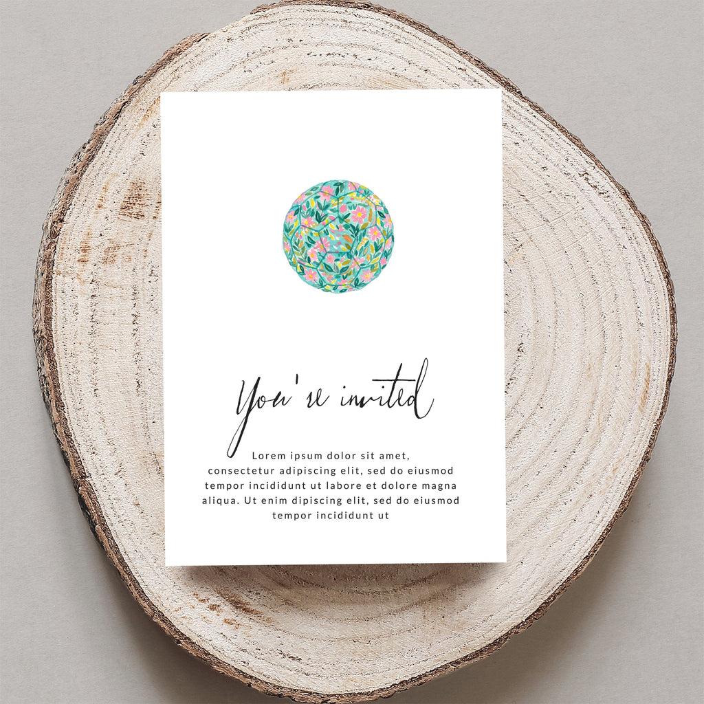 Invitation card with floral design and placeholder text, on a wood slice.