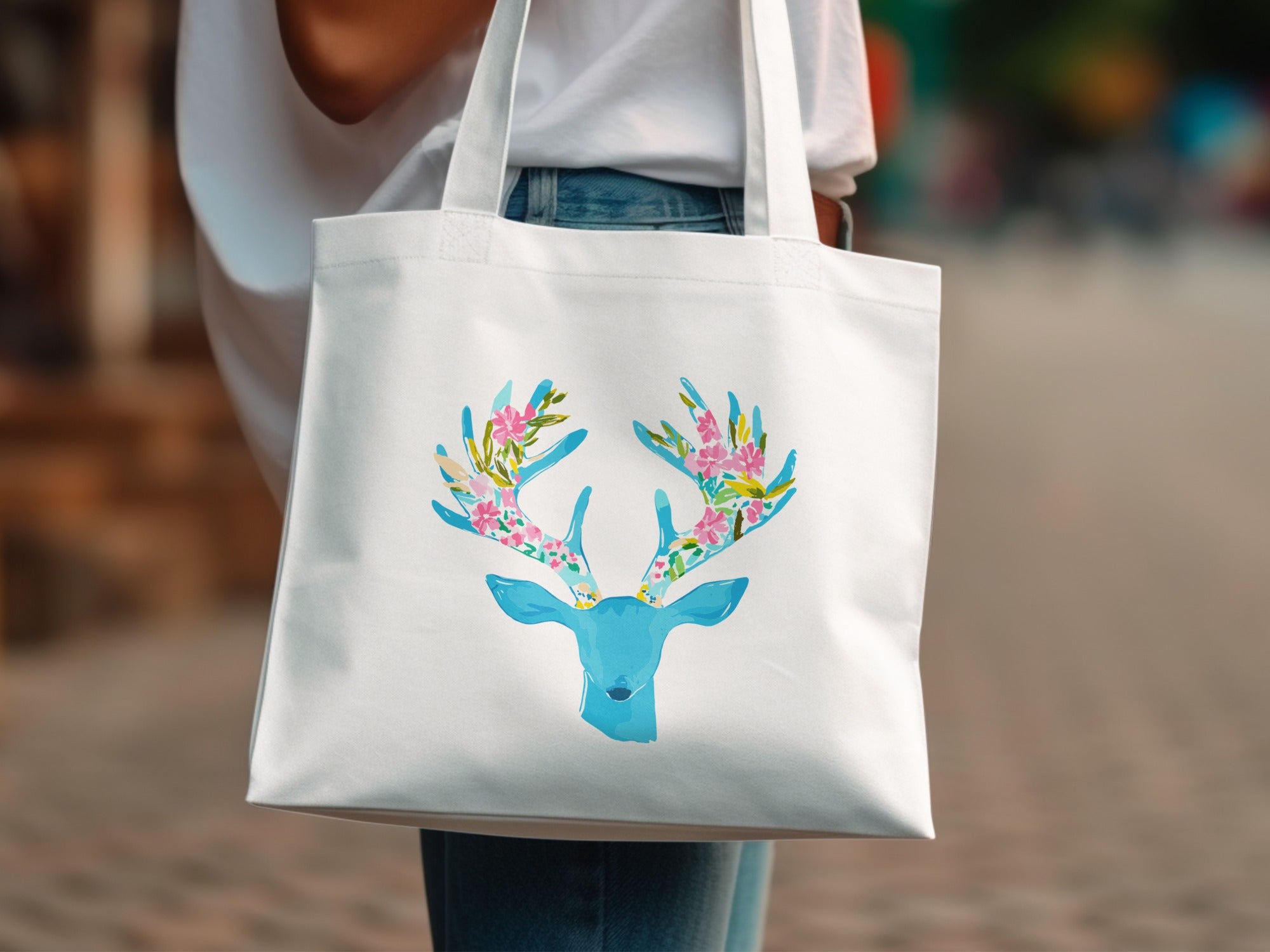 White tote bag with a blue deer head and floral antlers design.