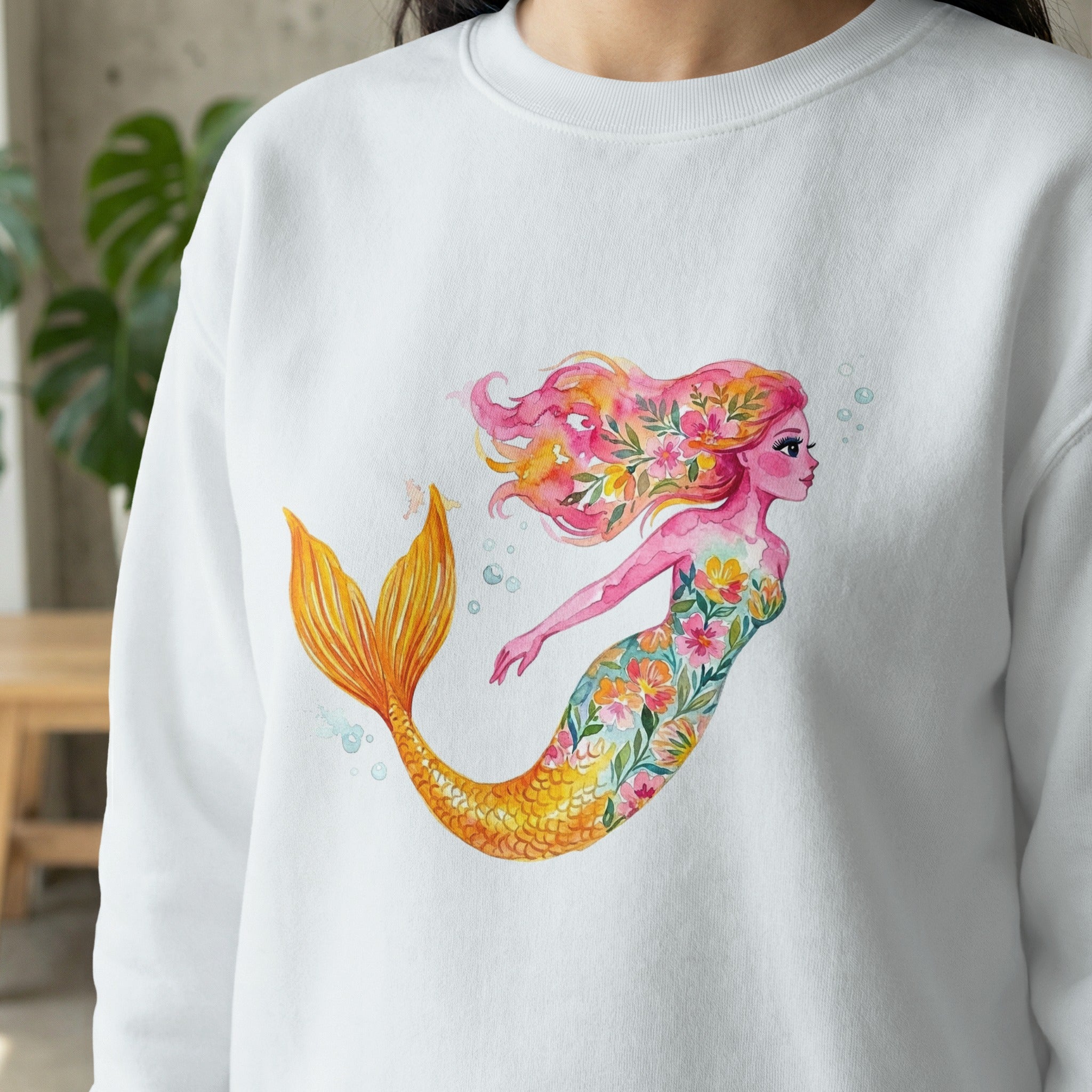 Watercolor mermaid with floral accents on a white sweatshirt.
