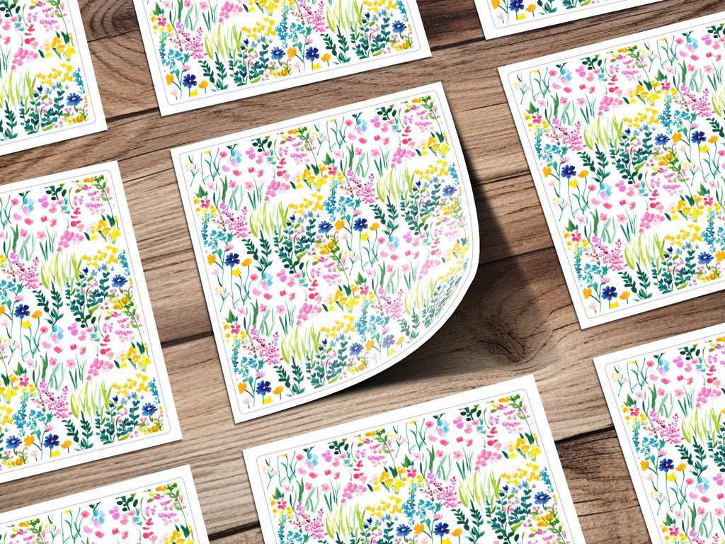 Several cards with a colorful watercolor floral pattern spread across a wooden surface.