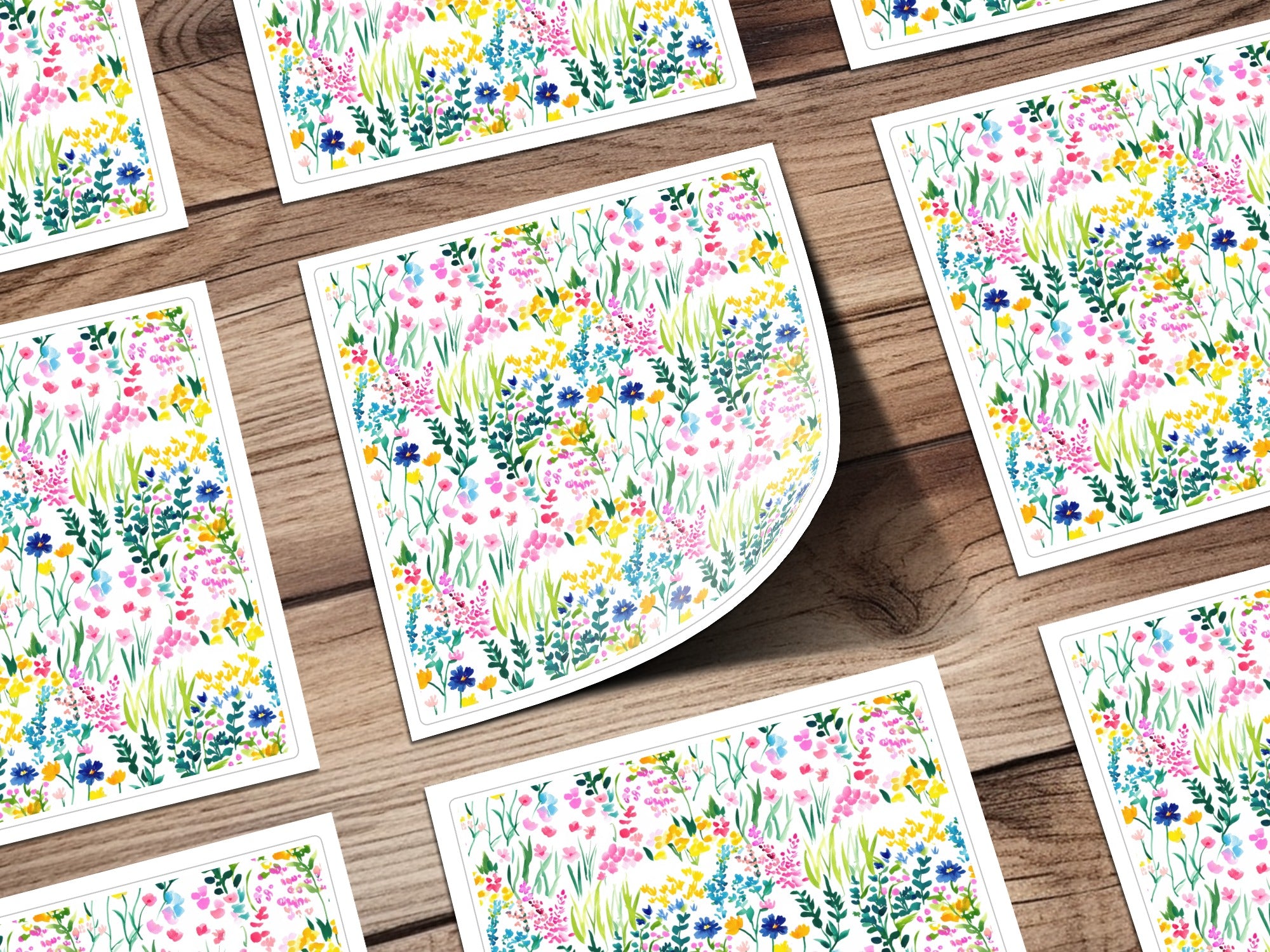 Several cards with a colorful watercolor floral pattern spread across a wooden surface.