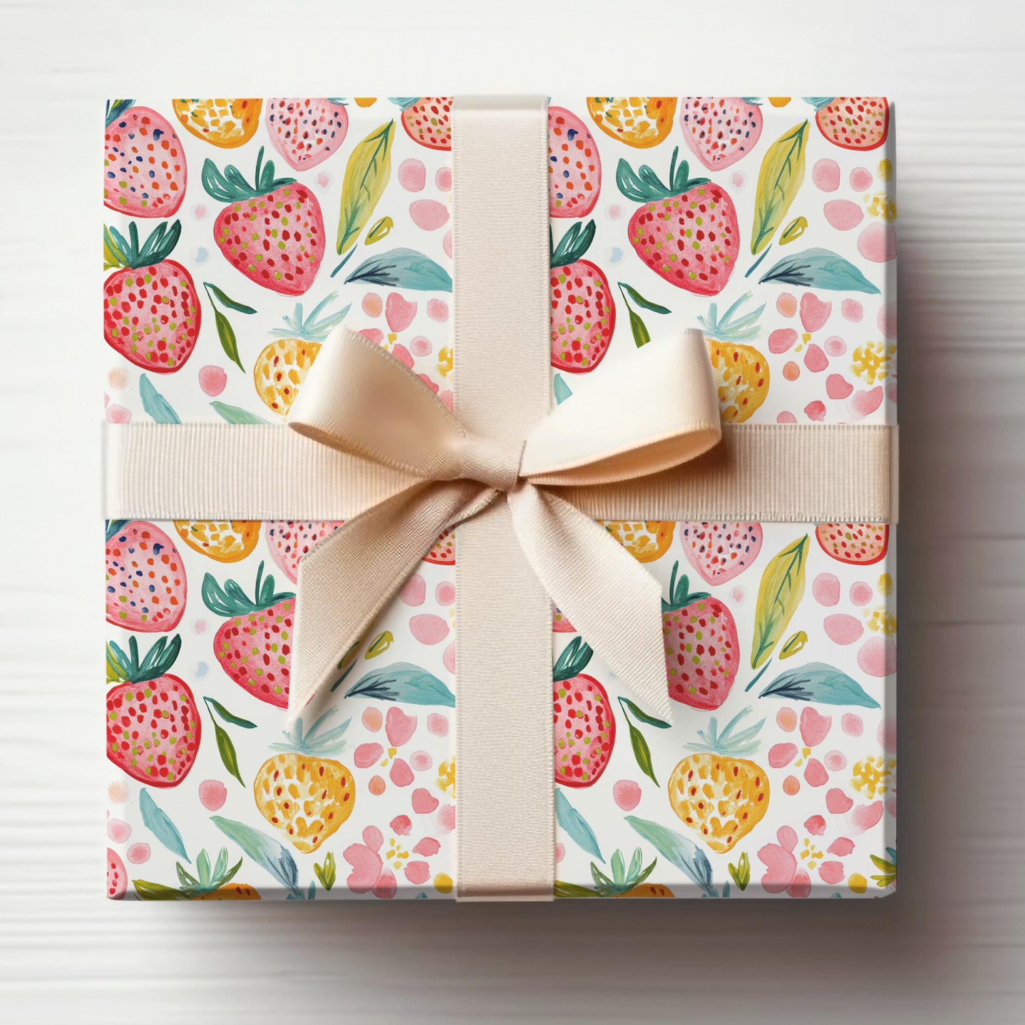 Gift-wrapped box with watercolor strawberry pattern and beige ribbon.