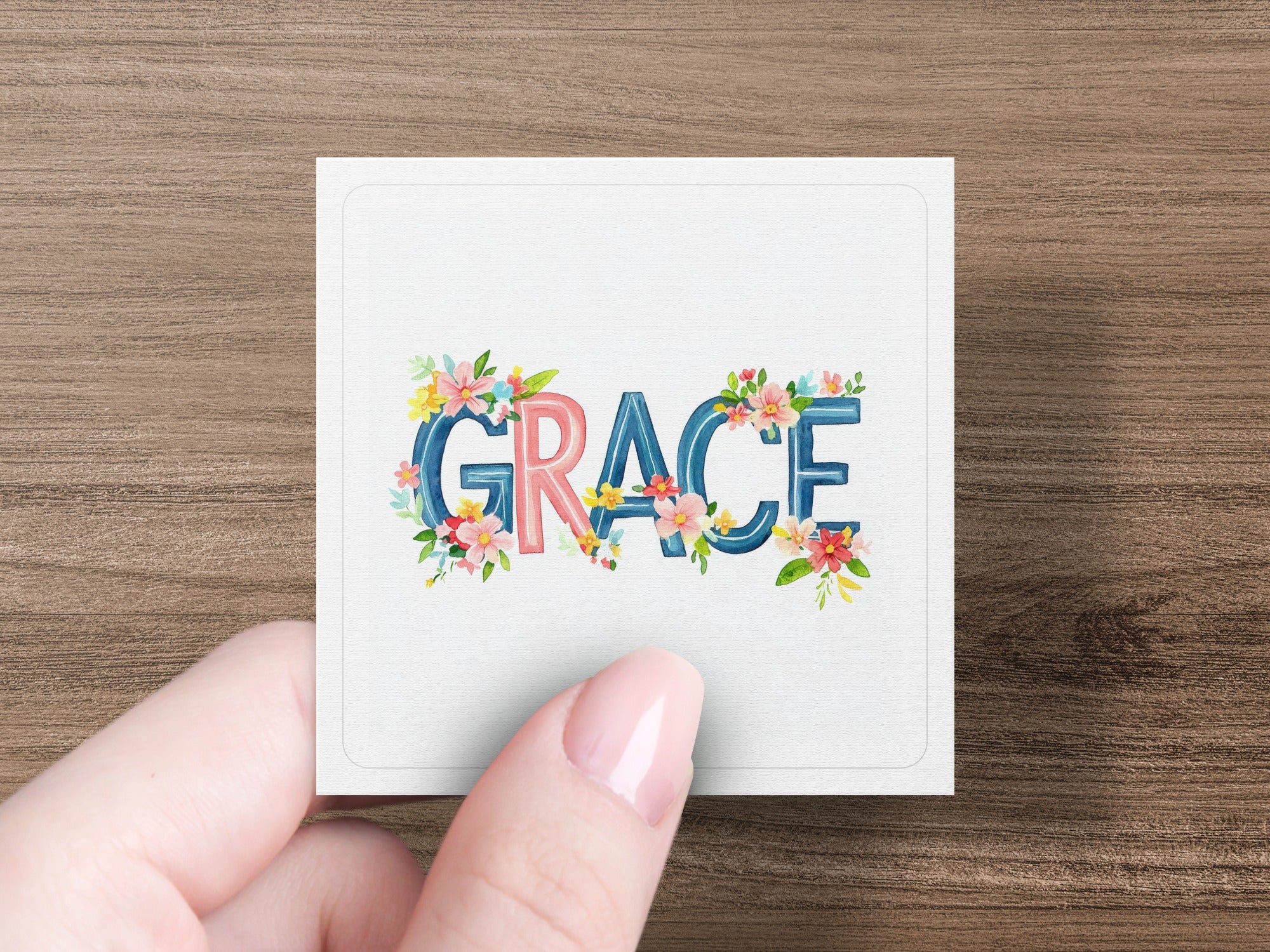 White card with "GRACE" in floral lettering held by a hand.