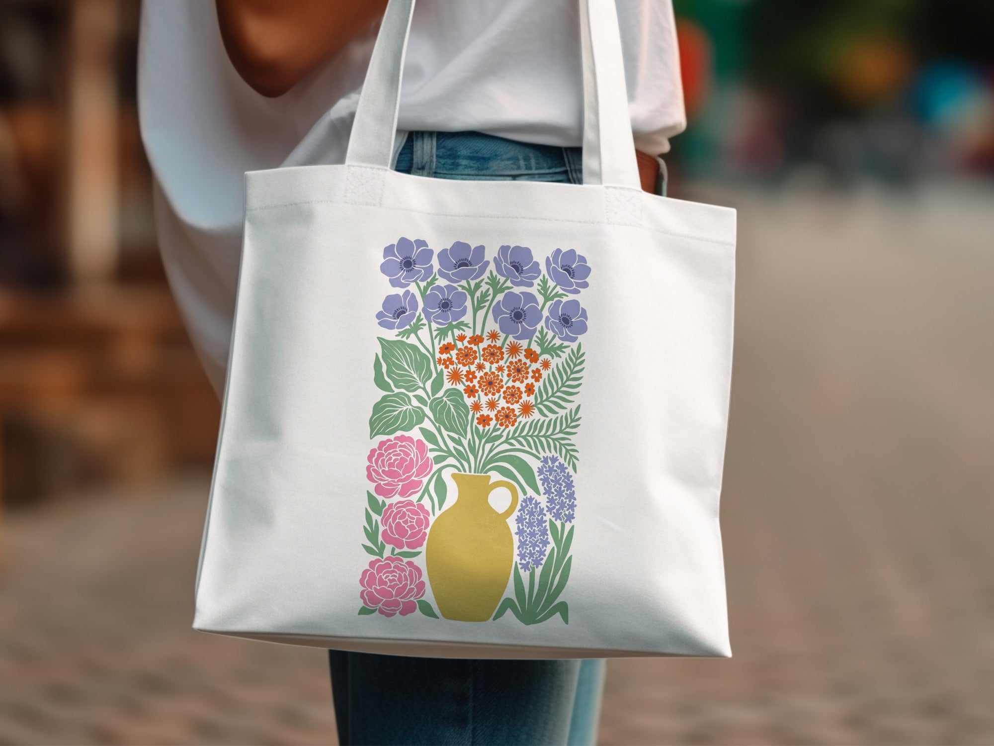 White canvas tote bag with colorful floral bouquet design in yellow vase.