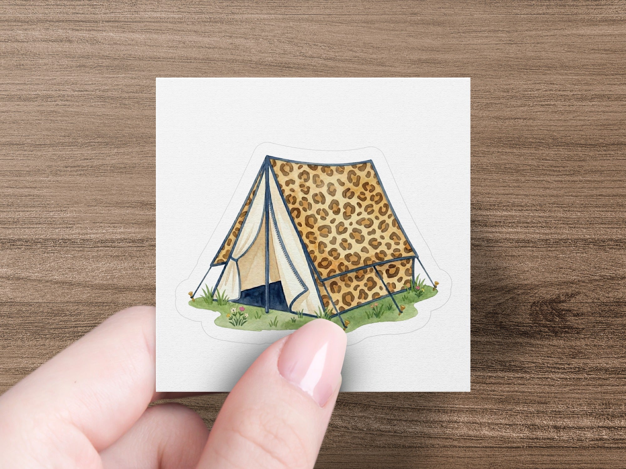 Leopard print tent with open flap on grass, held by a hand.