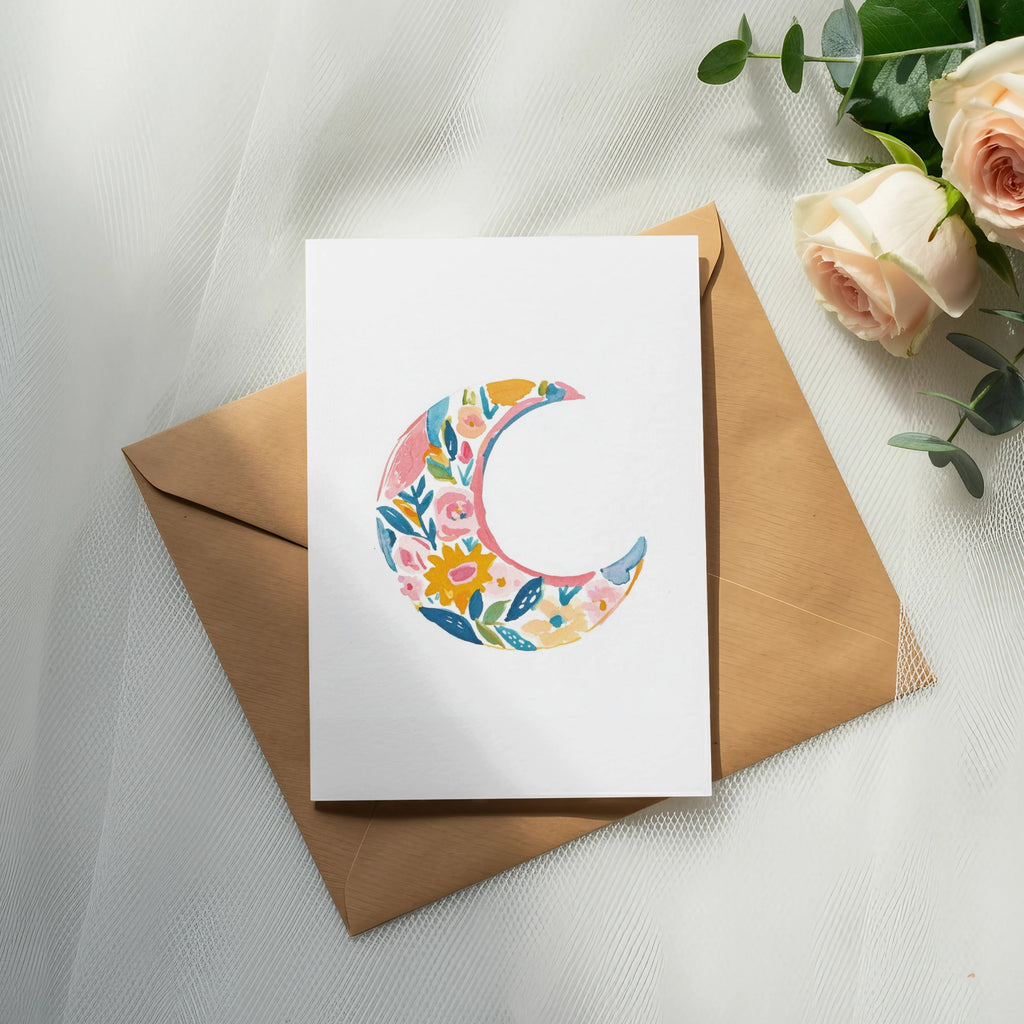 Floral crescent moon design on a white card with a brown envelope.