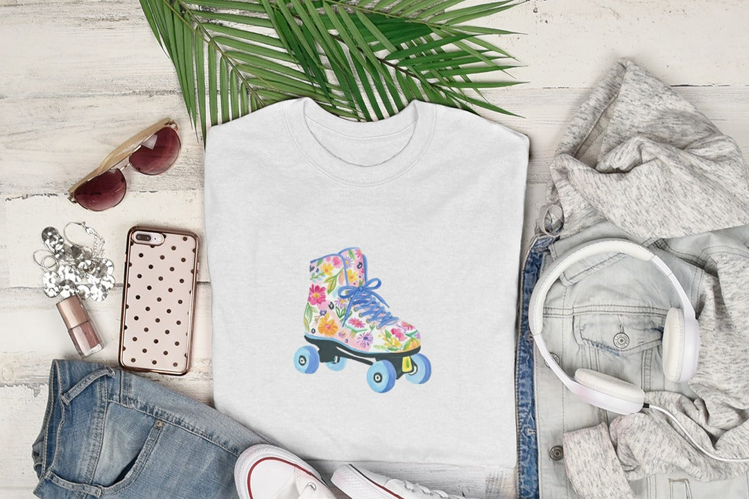 White t-shirt with watercolor roller skate design, sunglasses, headphones, and jeans.