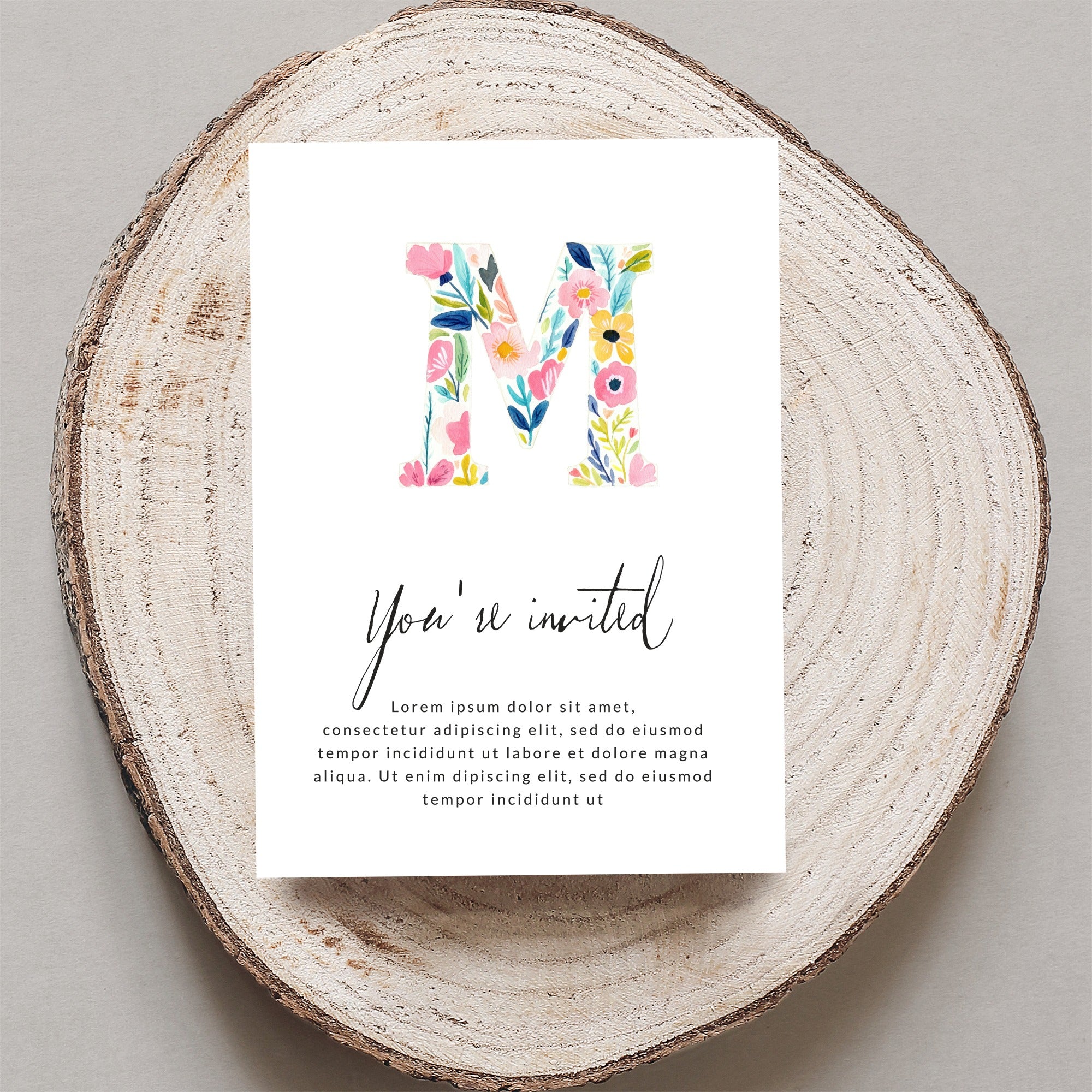 Floral letter M on invitation with "You're invited" text.