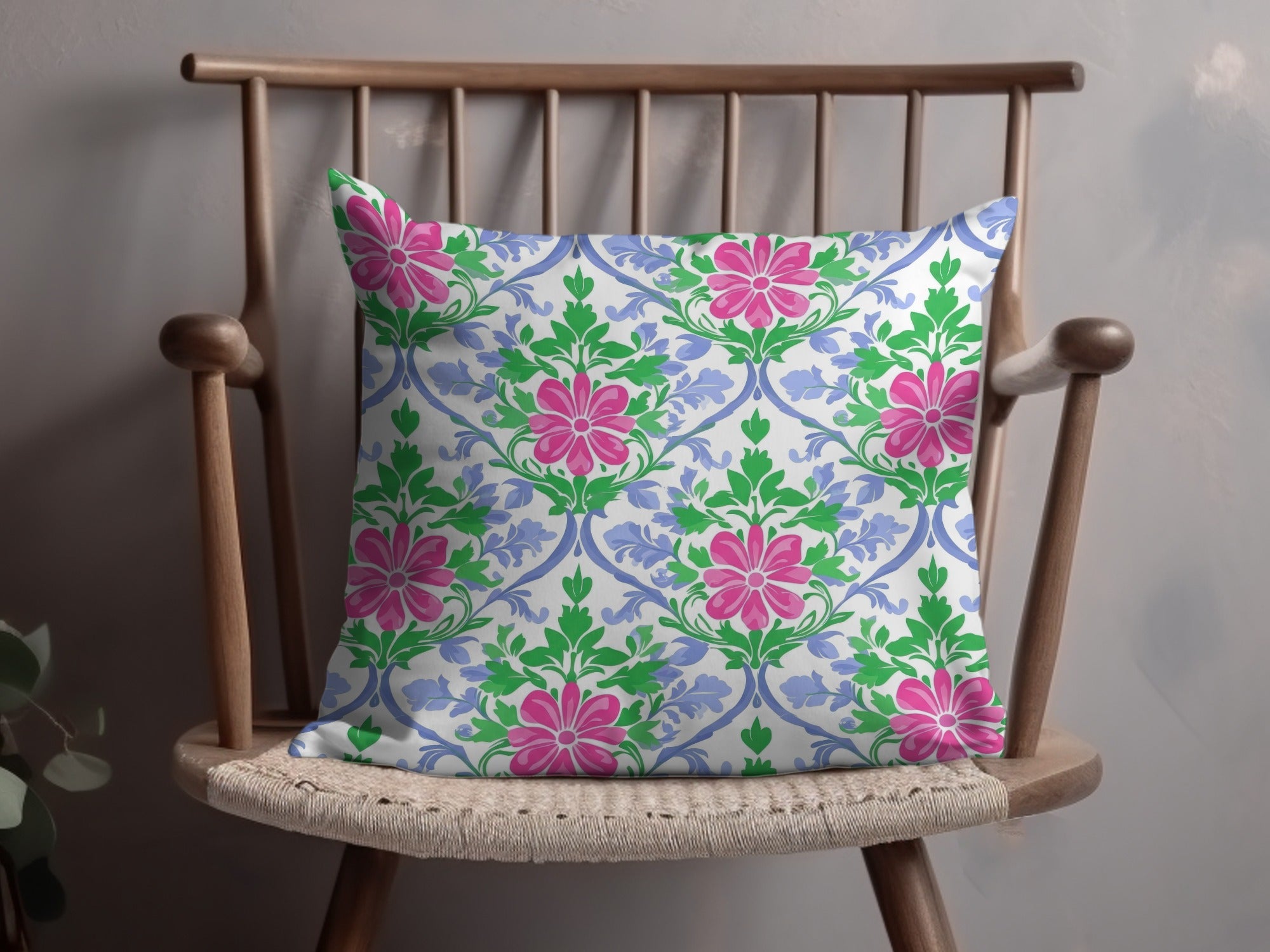 Throw pillow with pink floral and green leaf pattern on a wooden chair.