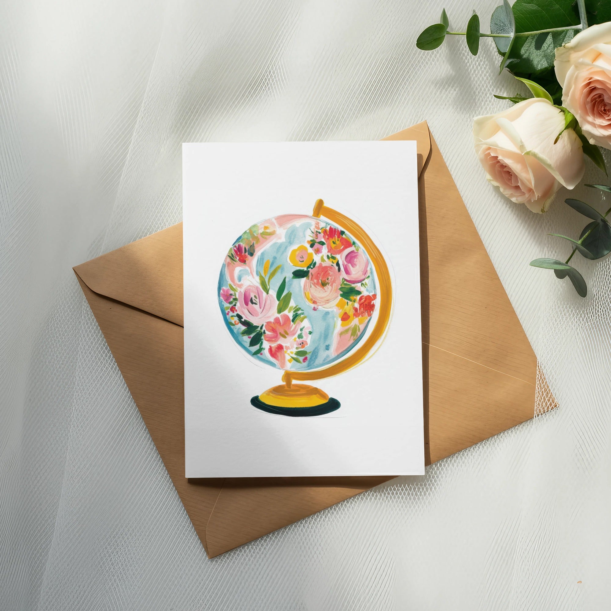 Watercolor globe with floral accents on a card in a kraft envelope.