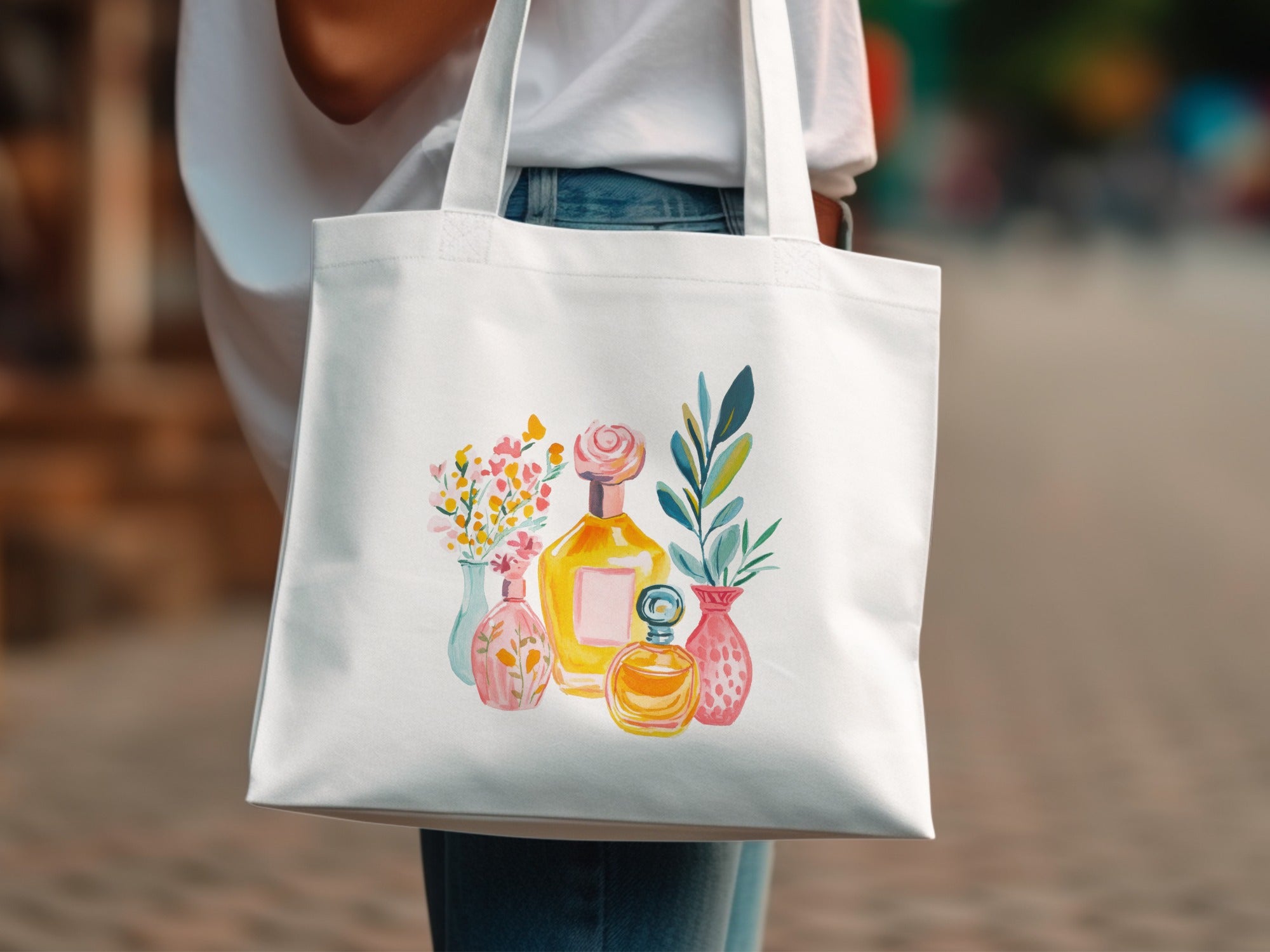 White tote bag with watercolor illustration of perfume bottles and flowers.