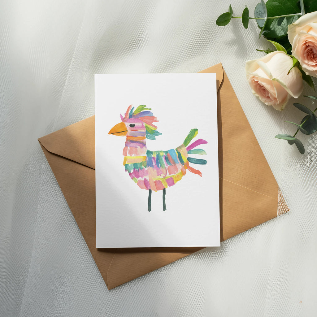 Card with colorful bird piñata illustration on brown envelope, with roses and greenery.
