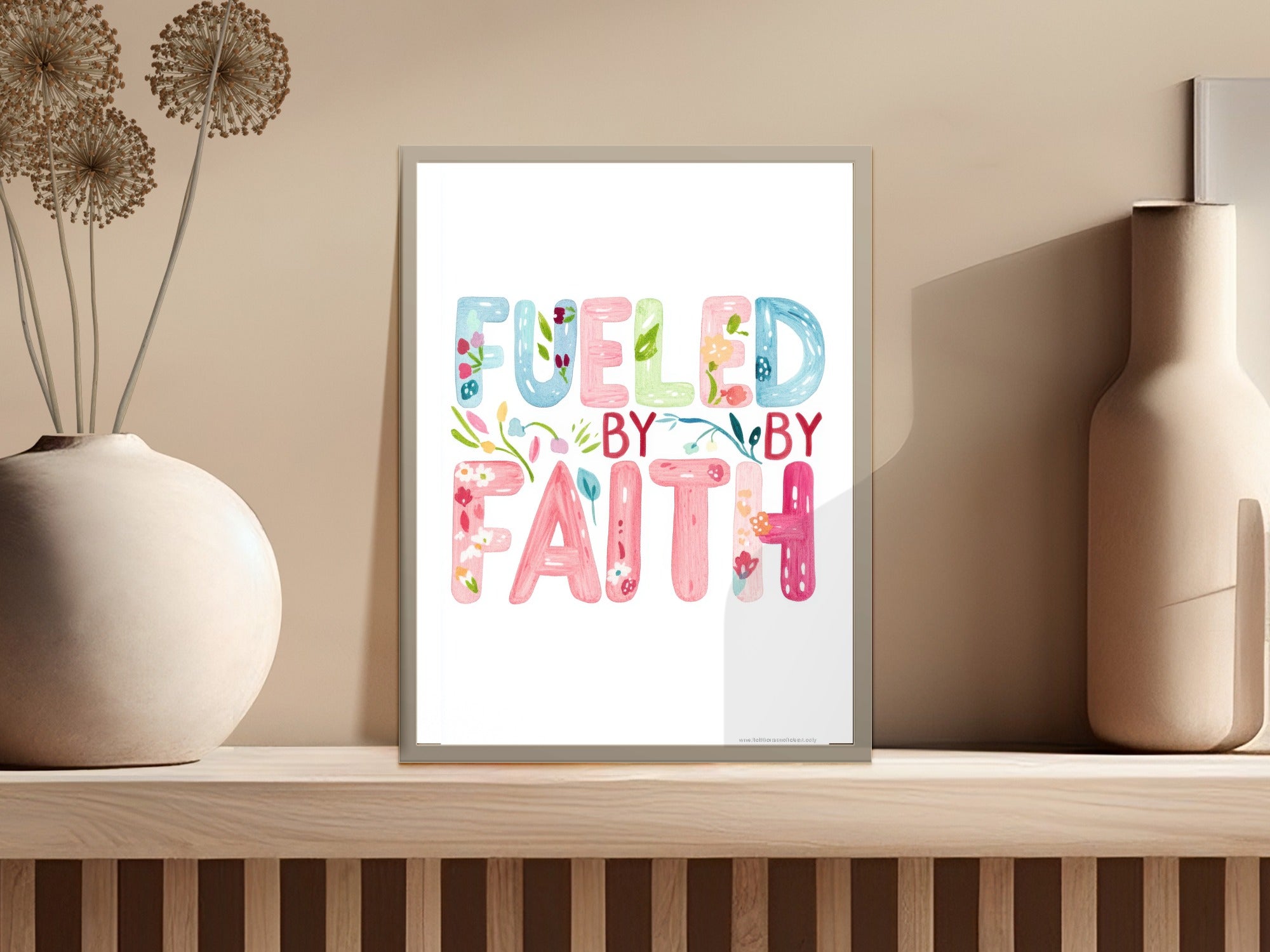 "Fueled by Faith" text art with floral accents and small plant in vase.