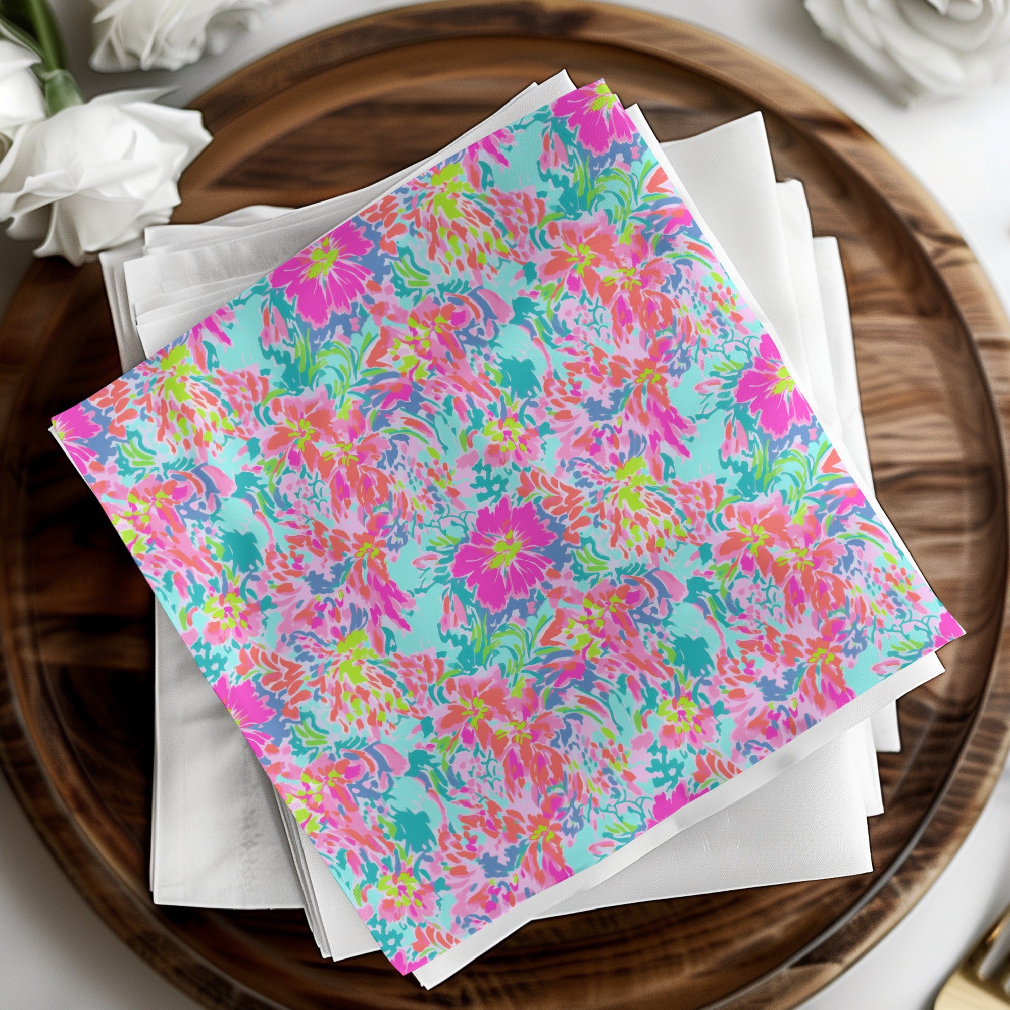 Bright floral pattern napkins on white napkins atop a wooden platter.