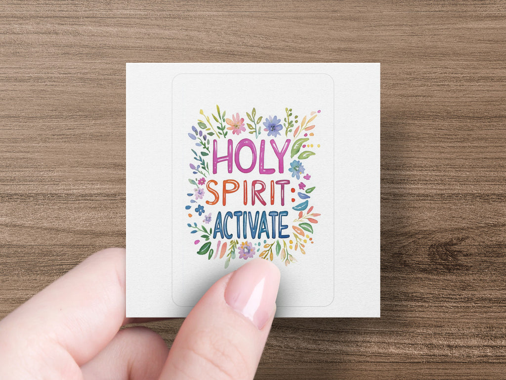 Hand holding square sticker with "HOLY SPIRIT: ACTIVATE" and floral design.