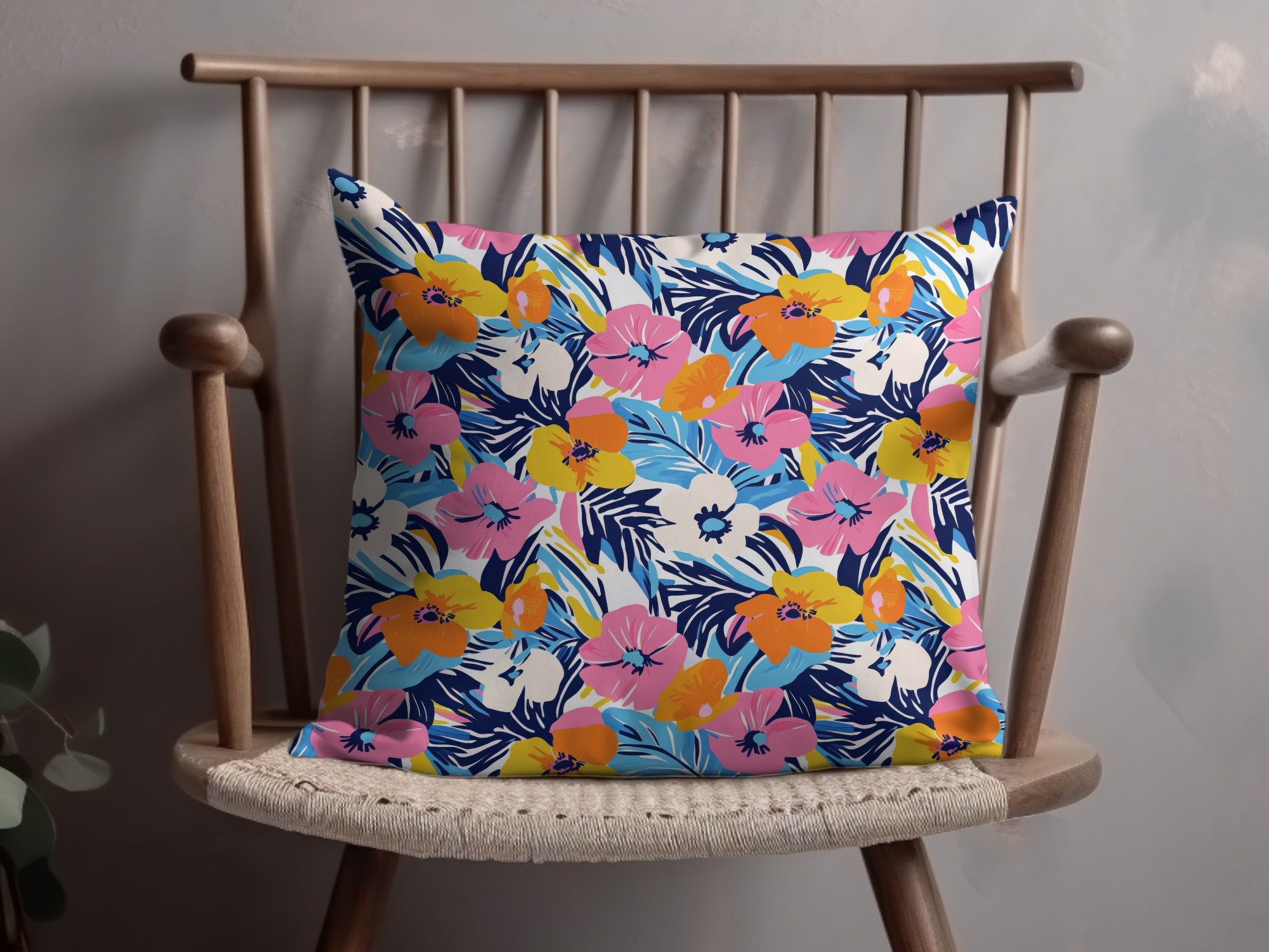 Floral throw pillow with blue, pink, yellow, and white flowers on a wooden chair.