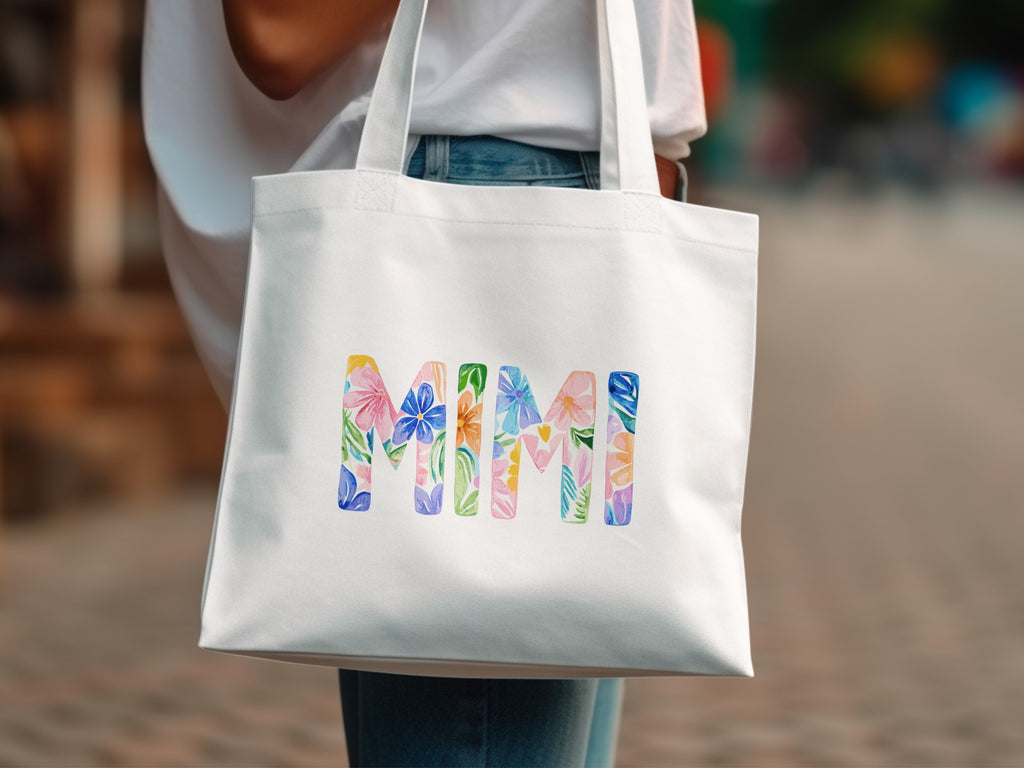 White tote bag with "MIMI" in colorful floral watercolor letters.
