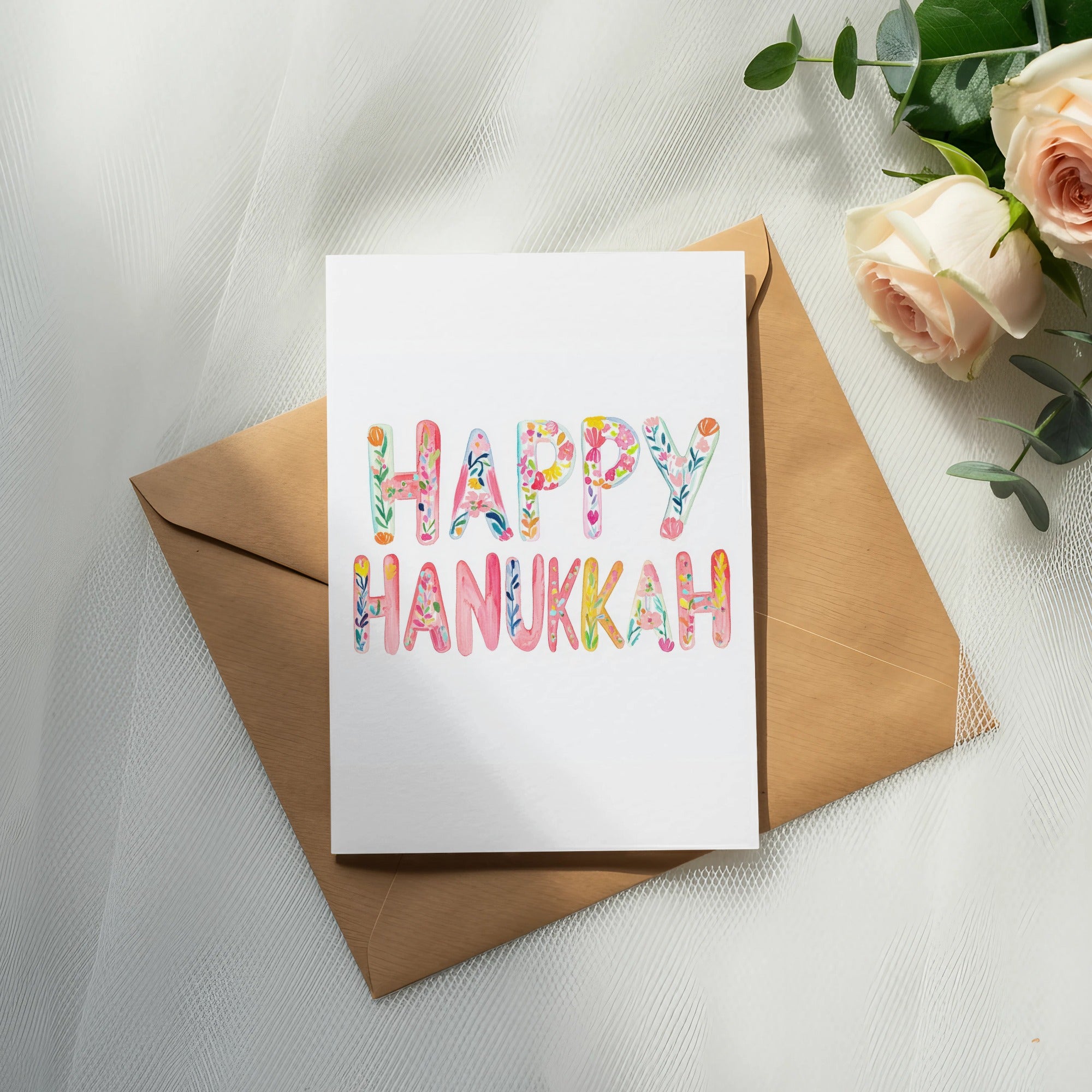 Greeting card with "Happy Hanukkah" in colorful floral lettering.