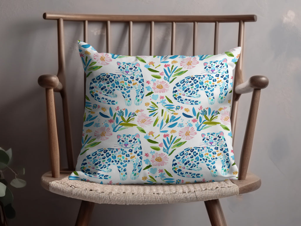 Watercolor pillow with leopards and floral pattern on a wooden chair.