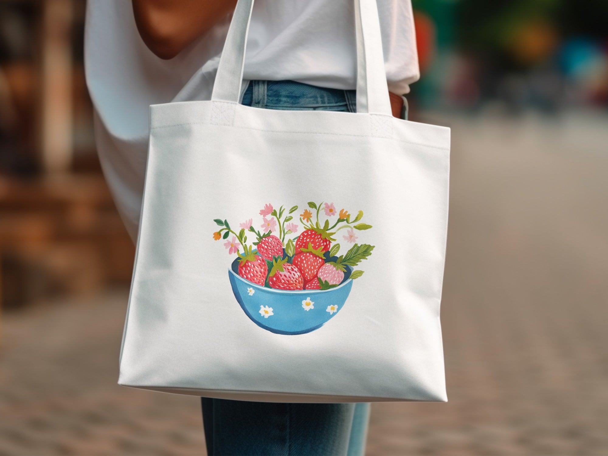 White canvas tote bag with a blue bowl filled with strawberries and flowers.