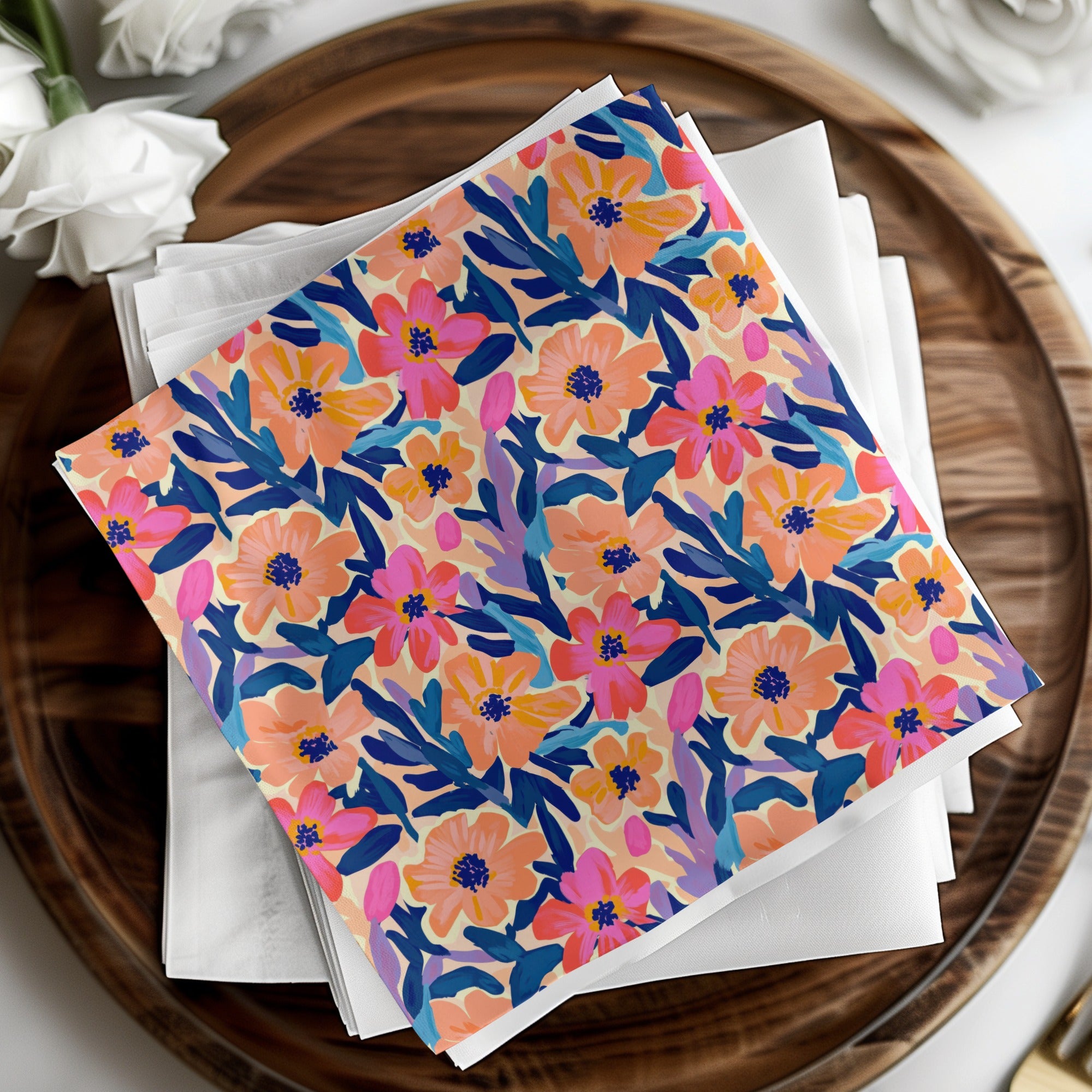 Floral patterned cocktail napkin on white napkins and wooden tray.