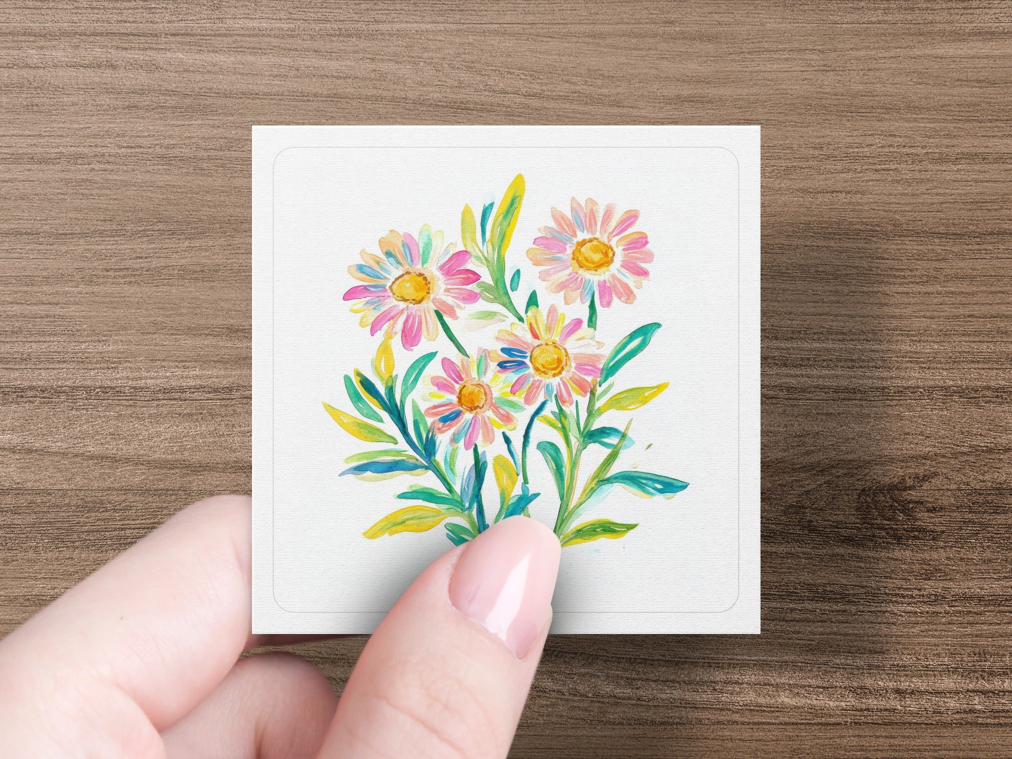 Watercolor painting of colorful daisies with green leaves on a white card.