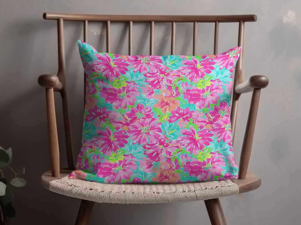 Pink and blue floral pillow on a wooden chair.