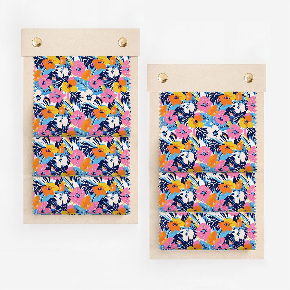 Two fabric swatches with a vibrant floral pattern on a wooden board.