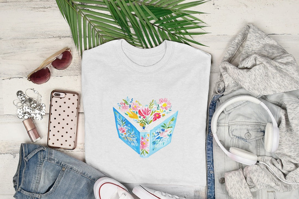White t-shirt with open book and colorful flowers design.