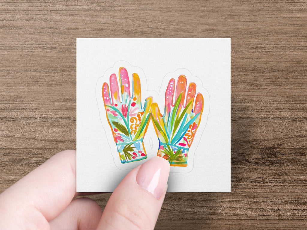 Decorative gardening gloves with floral patterns held by a hand.