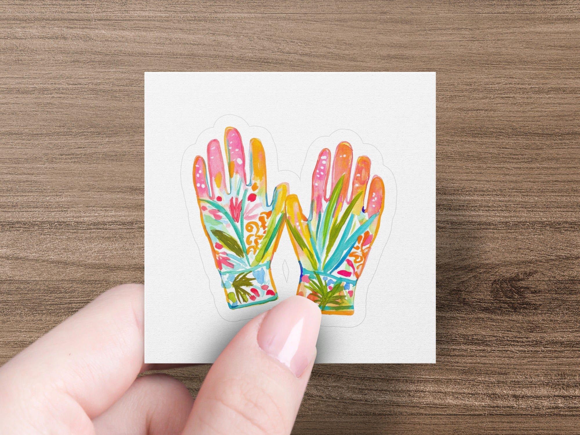 Decorative gardening gloves with floral patterns held by a hand.