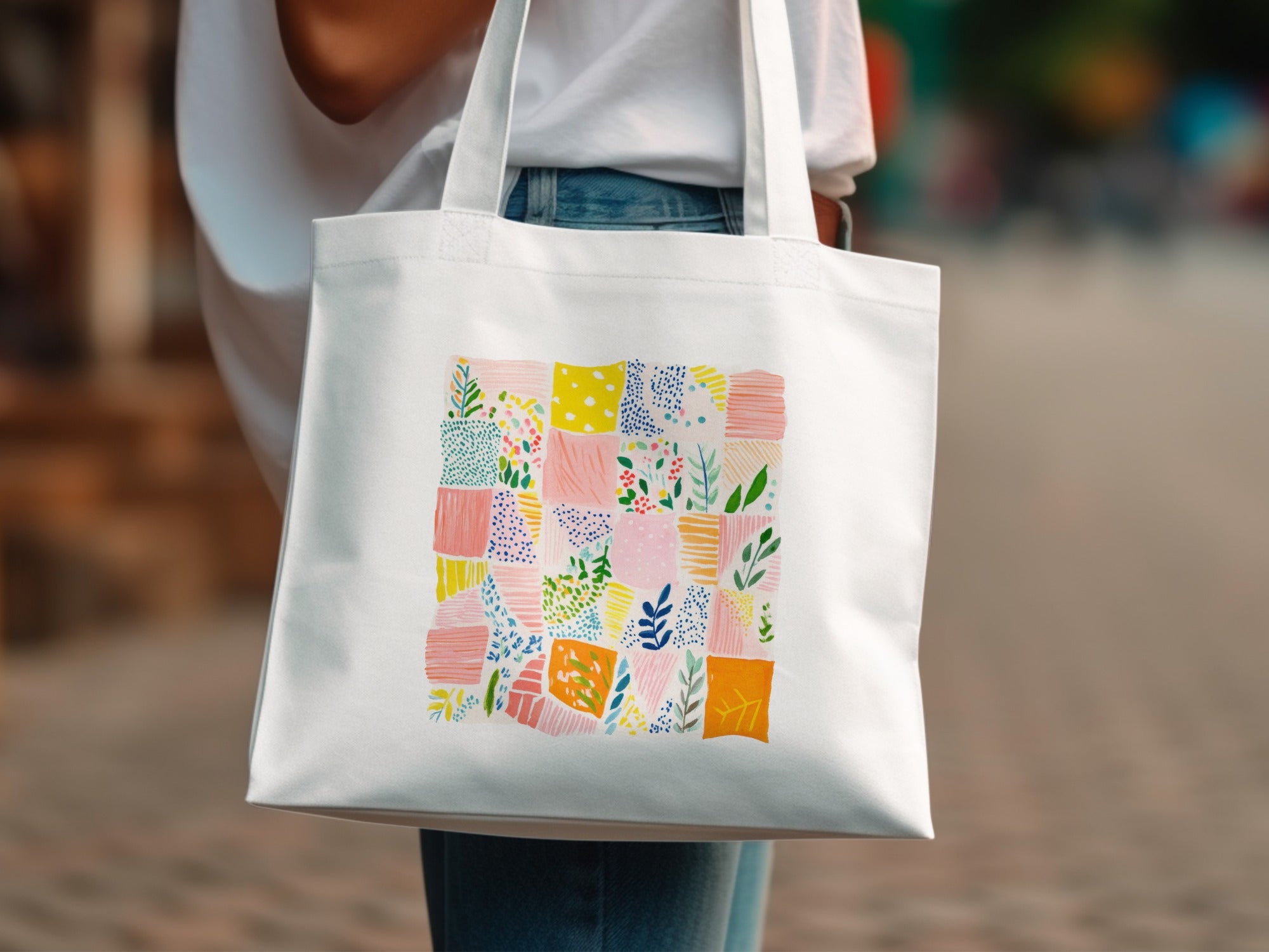 White canvas tote bag with a colorful patchwork quilt-style pattern.