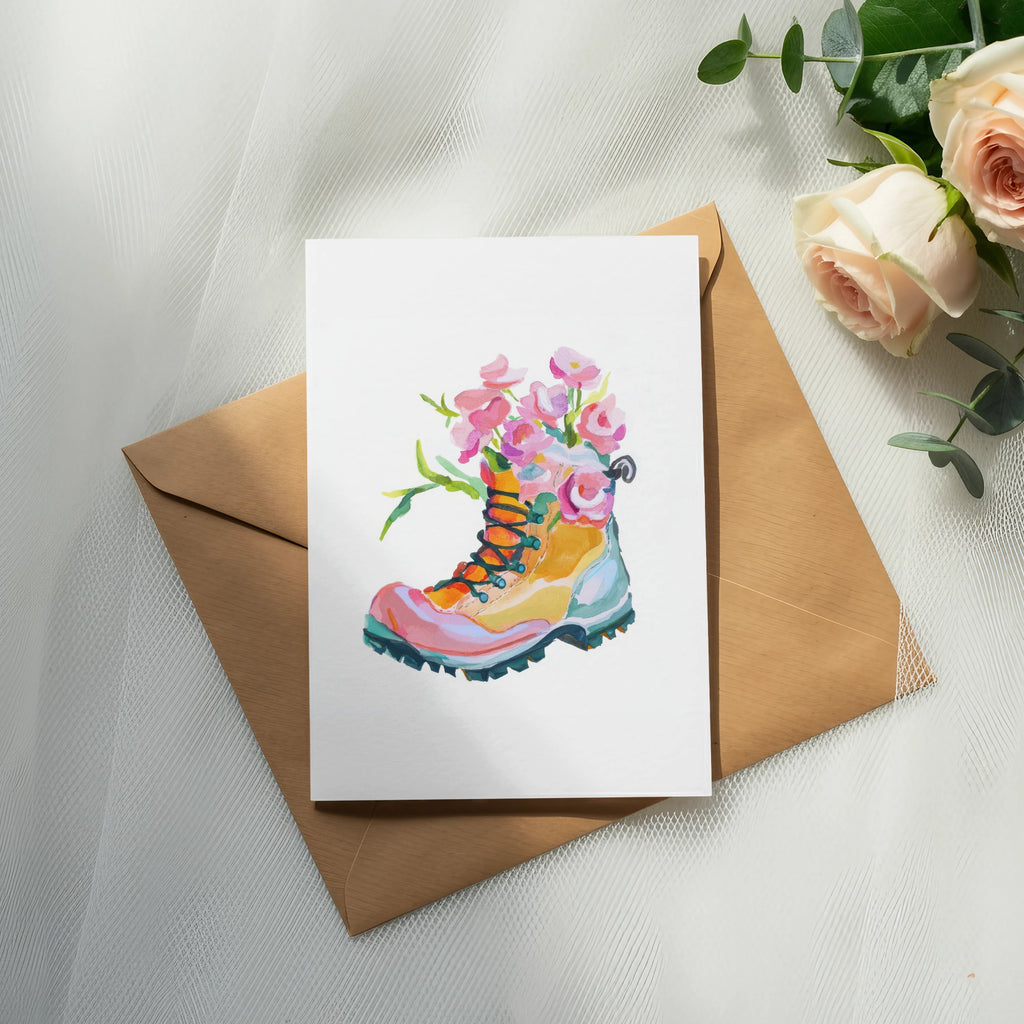 Watercolor painting of a colorful hiking boot with flowers on a card.