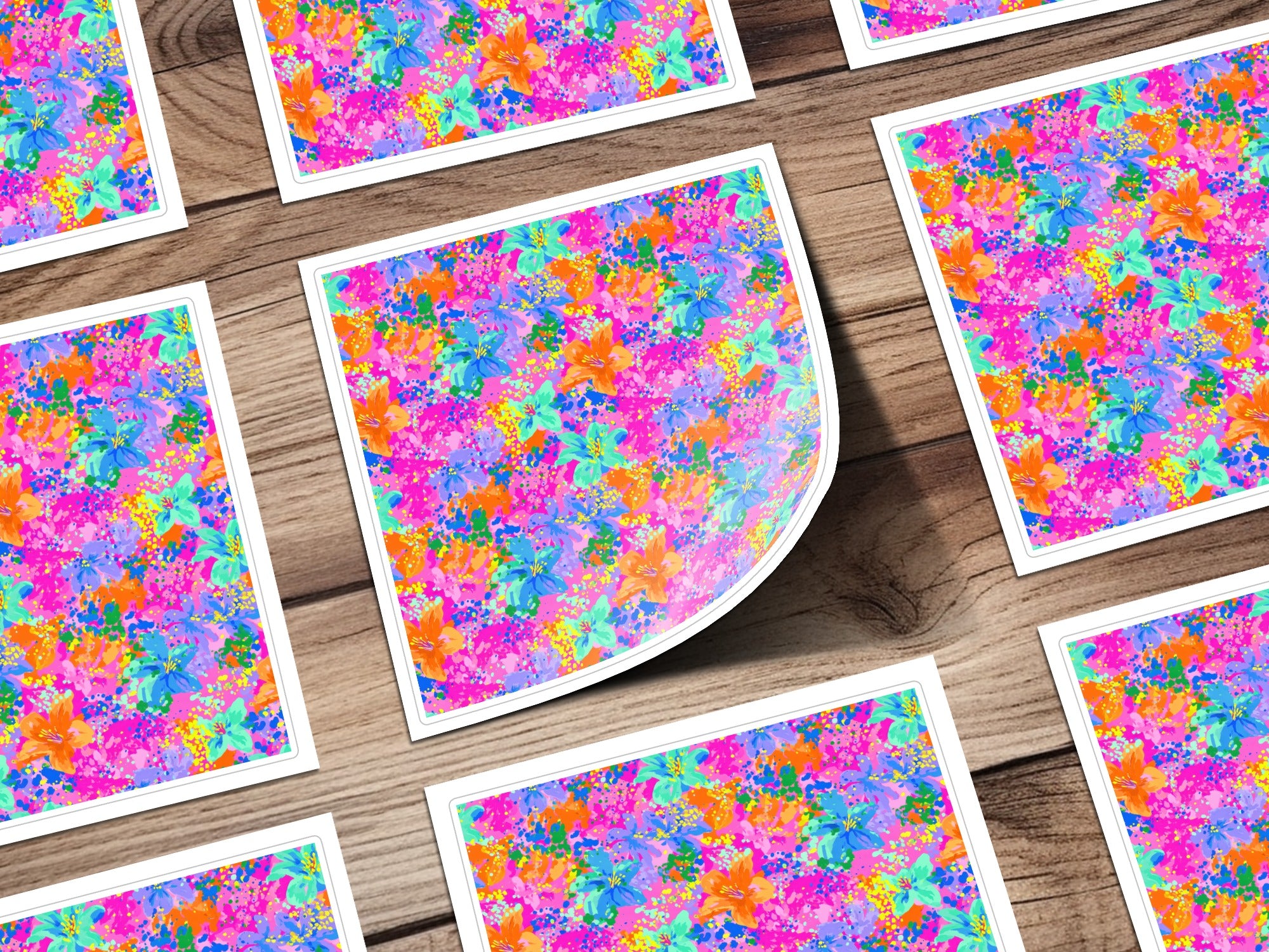 Multiple square stickers with a vibrant floral pattern on a wooden background.