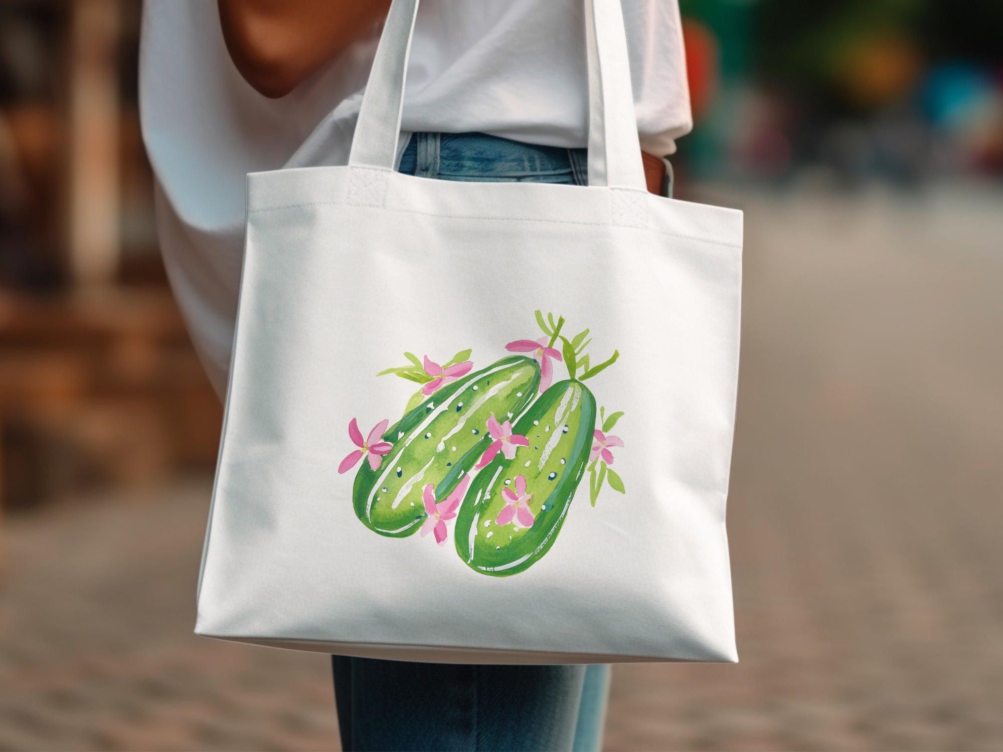 White tote bag with a watercolor illustration of two cucumbers and pink flowers.
