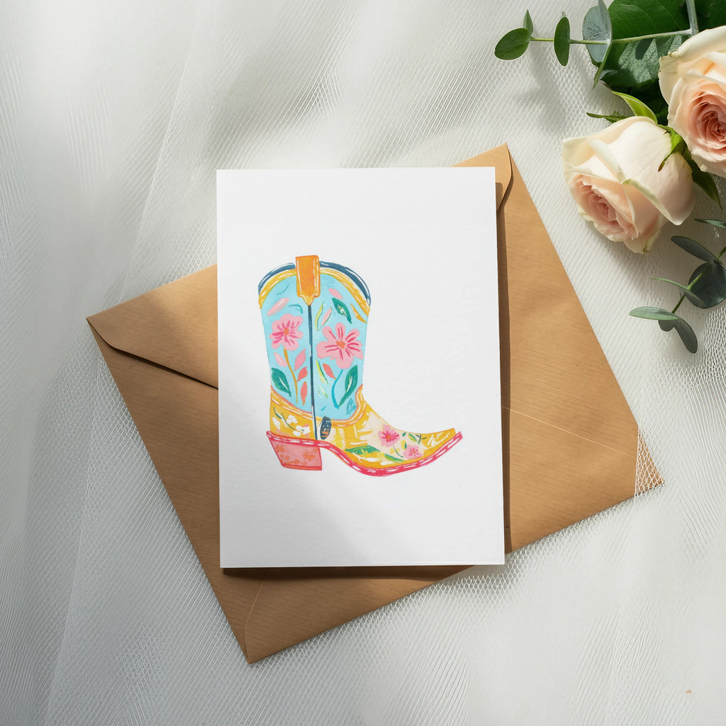 Colorful cowboy boot illustration on white card over brown envelope with roses.