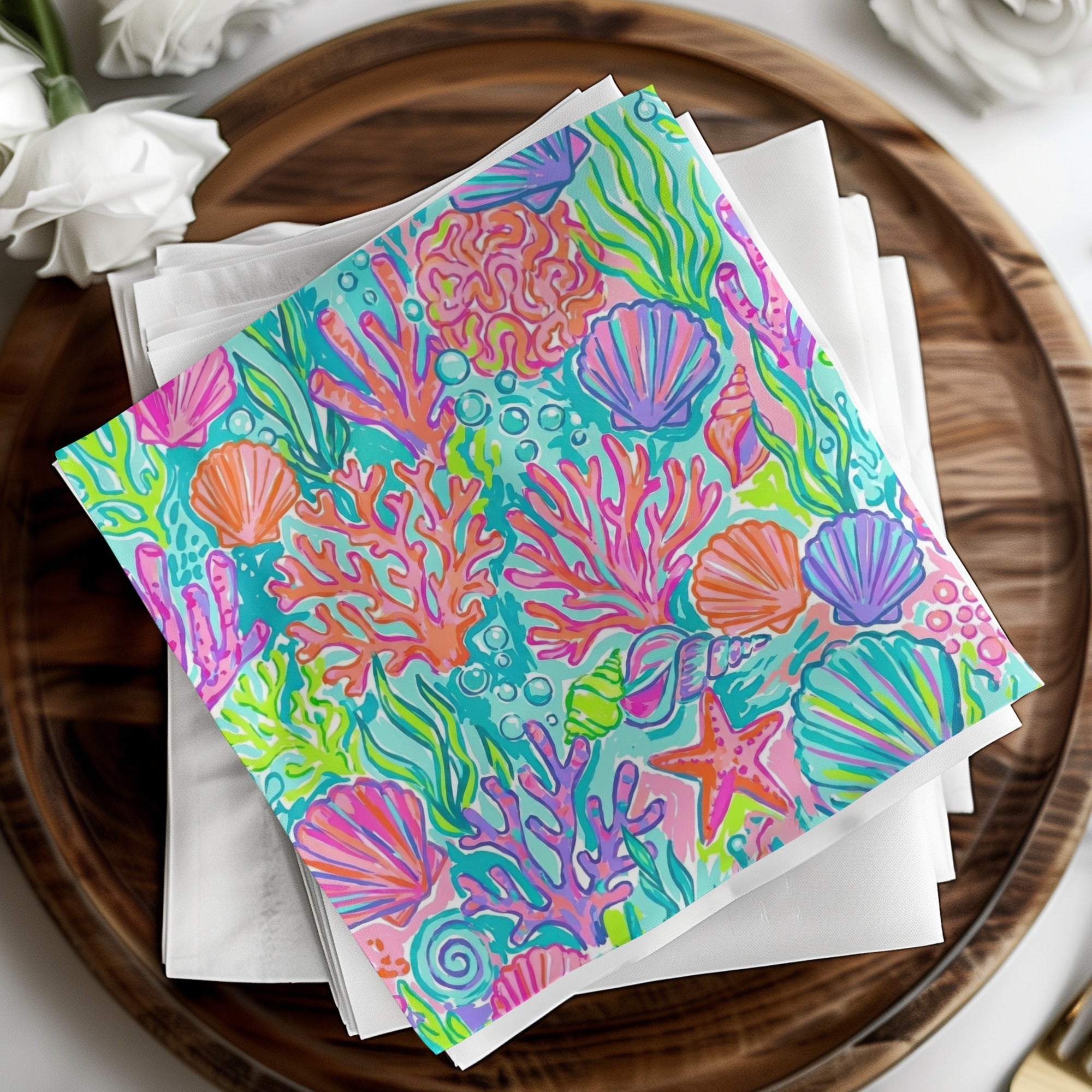Colorful coral and seashell pattern on folded napkins, arranged on a wooden tray.