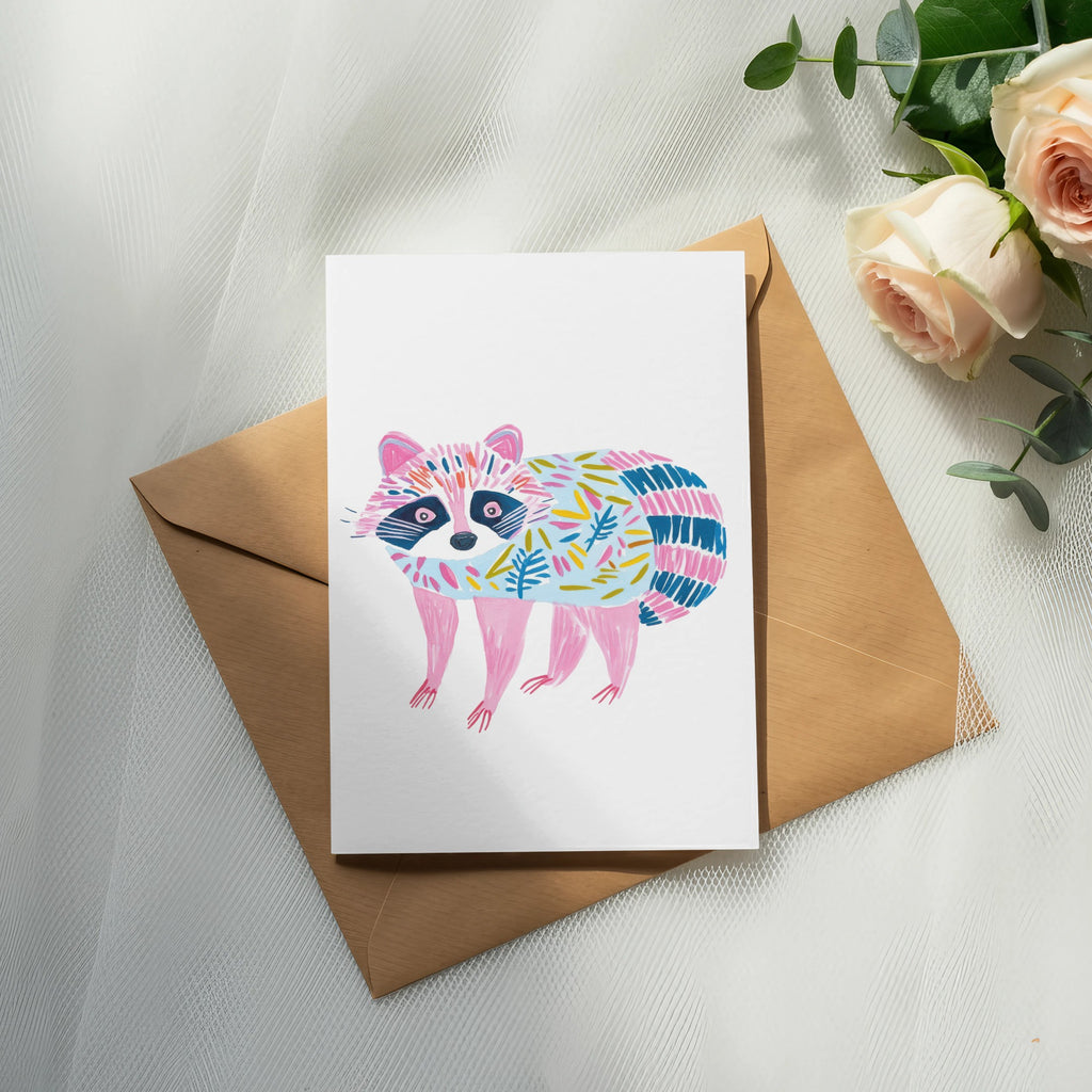 Illustration of a raccoon with pink, blue, and green patterned fur on a card.