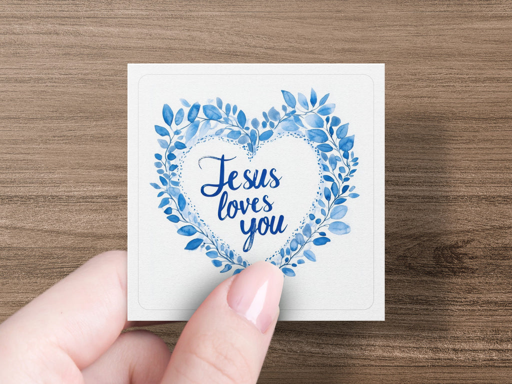 Heart wreath with "Jesus loves you" text held by a hand.