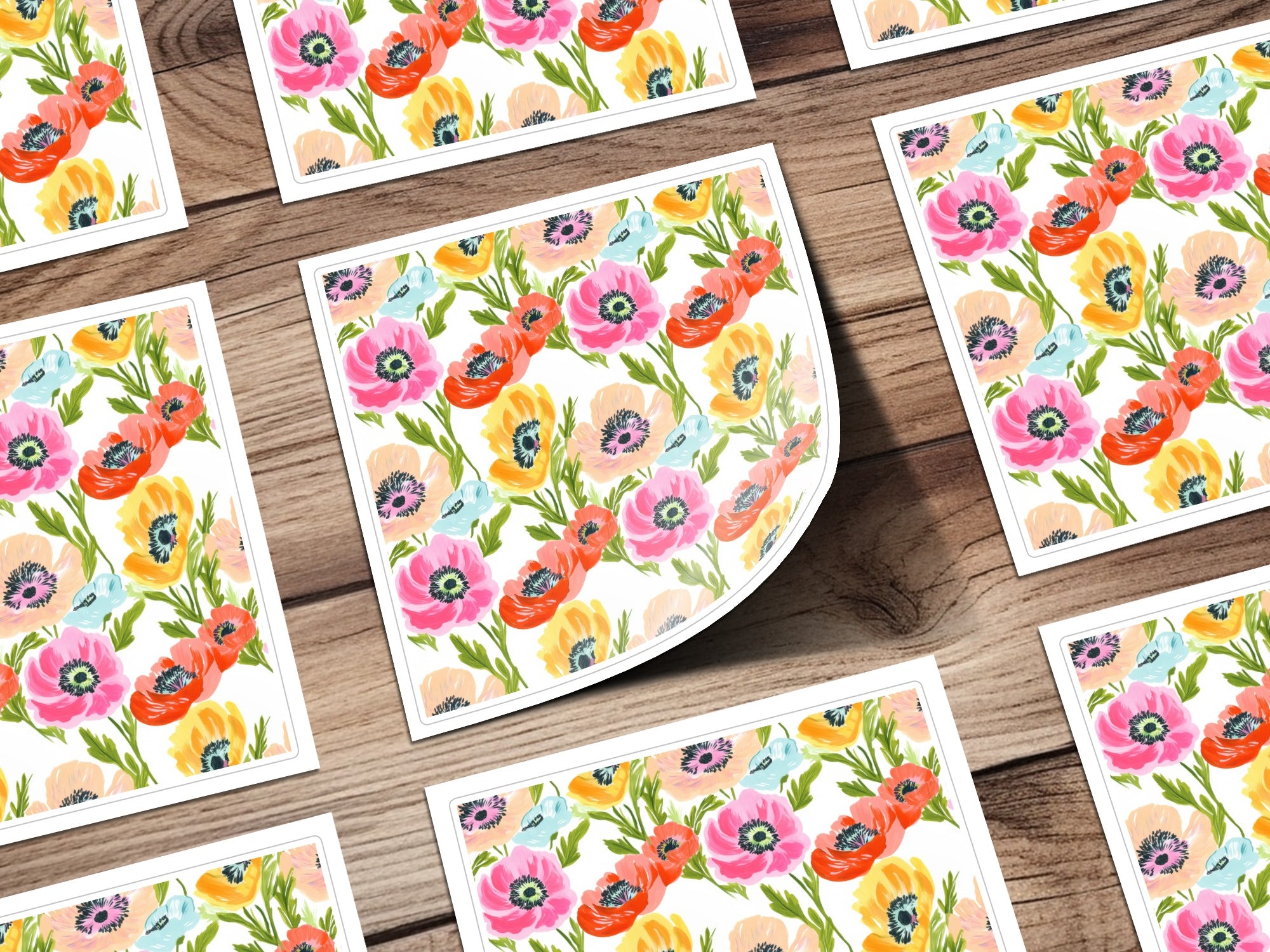 Floral pattern of poppies on cards arranged on a wooden surface.