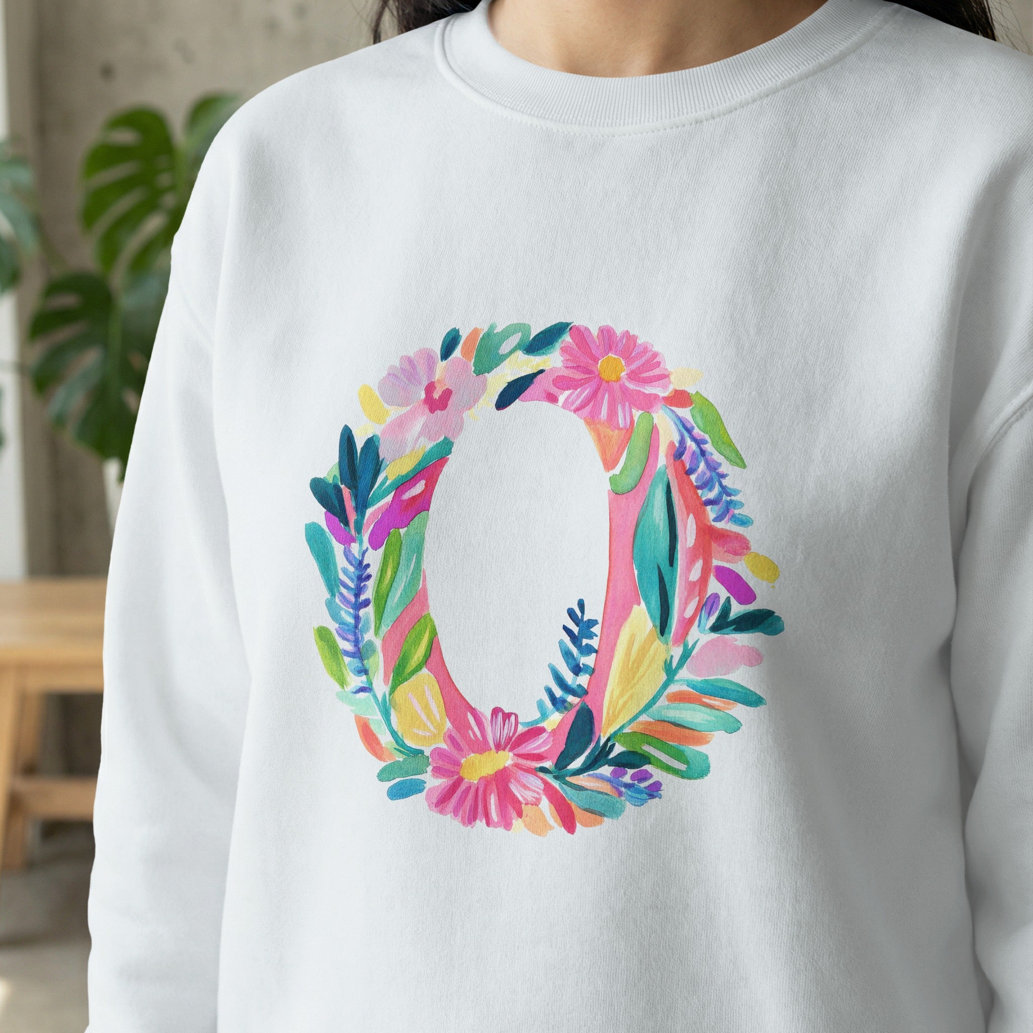 White sweatshirt with a large, colorful floral letter O design.