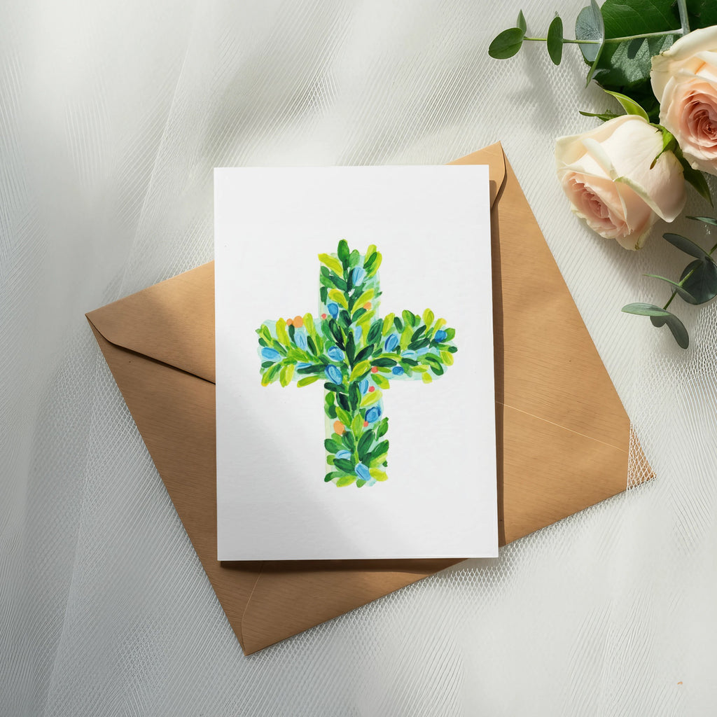 Watercolor cross with green leaves and blue accents on card, with envelope and roses.
