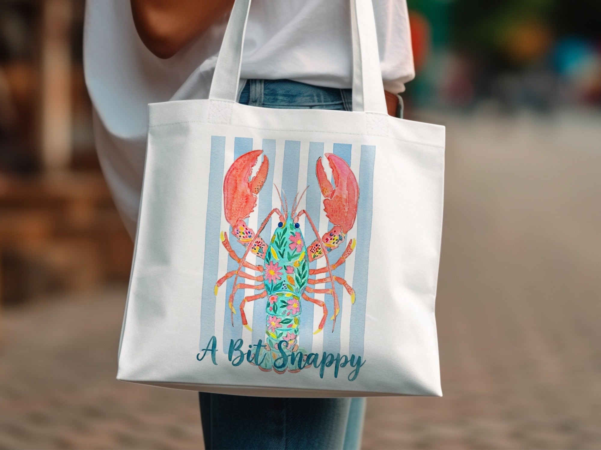 White tote bag with floral lobster design and text "A Bit Snappy".