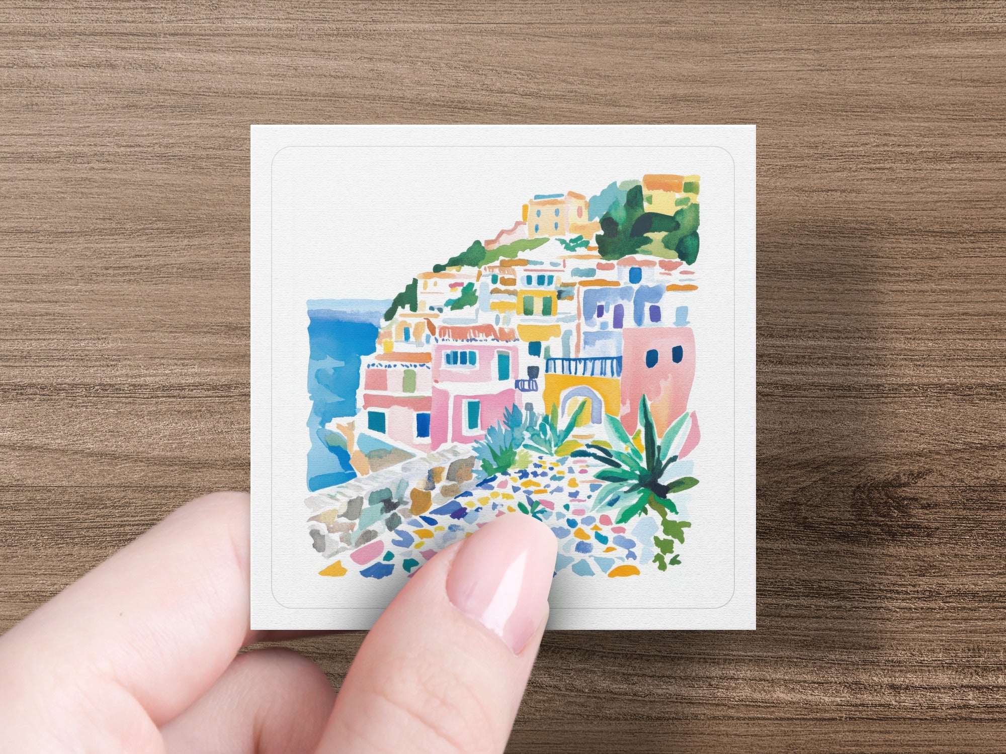 Watercolor painting of a colorful coastal village with buildings cascading down a hill.