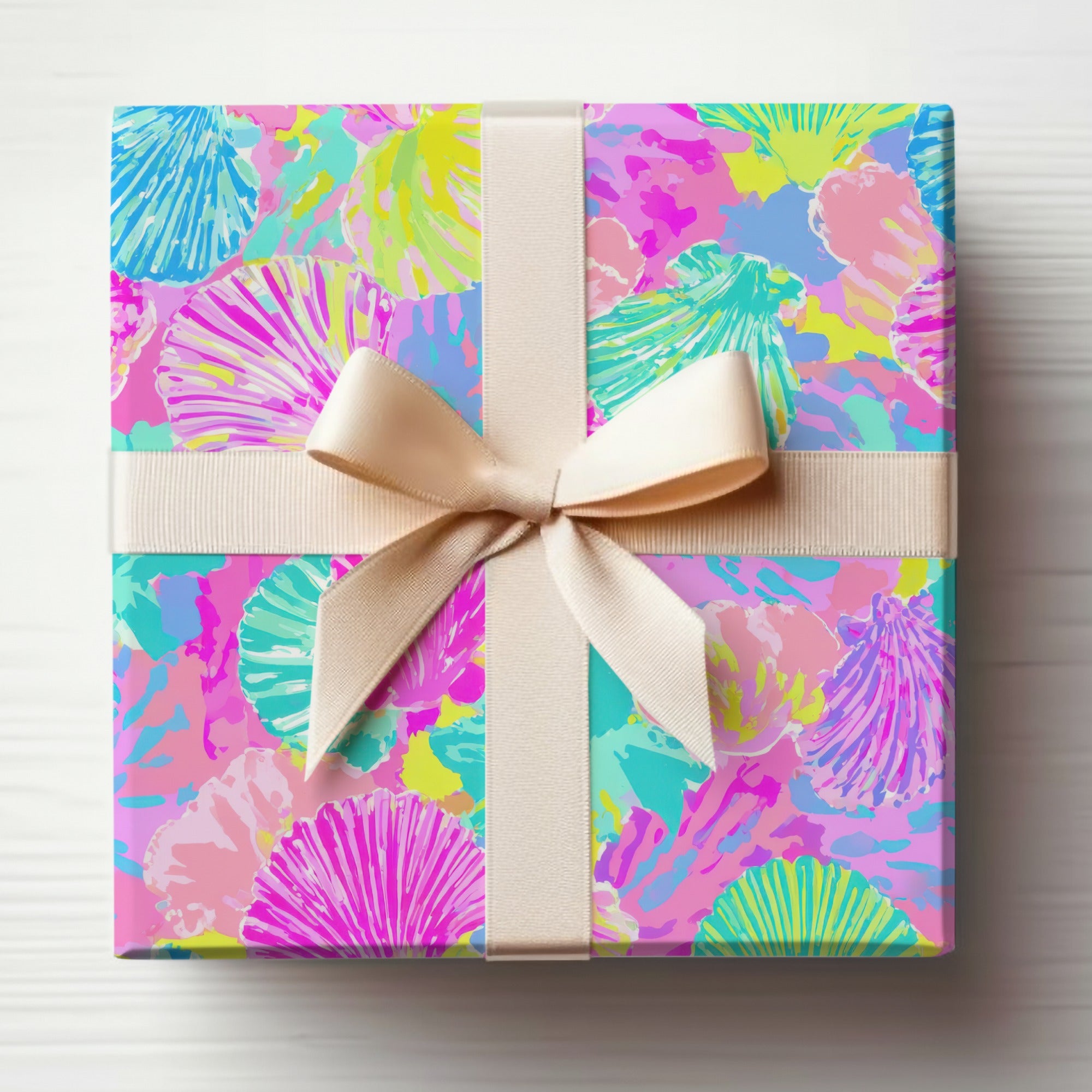 Gift box wrapped in colorful seashell pattern with a beige ribbon.
