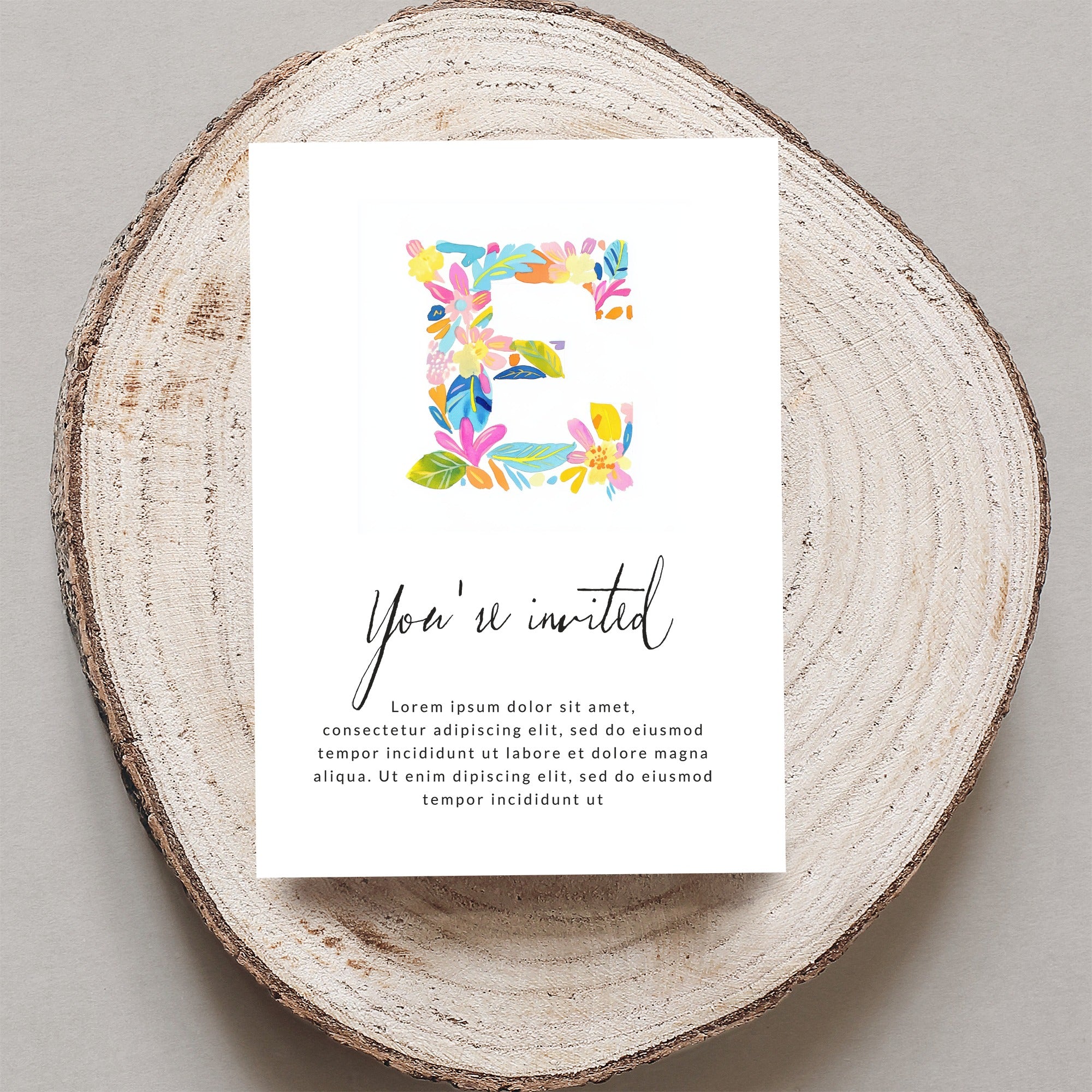 Invitation with colorful floral initial E and placeholder text.