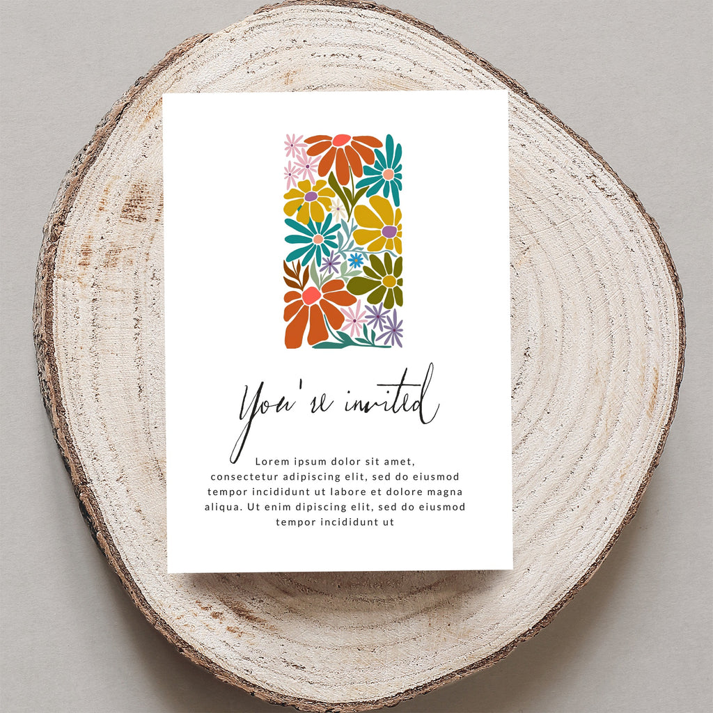 Invitation card with "You're invited" text and floral design on wood slice.