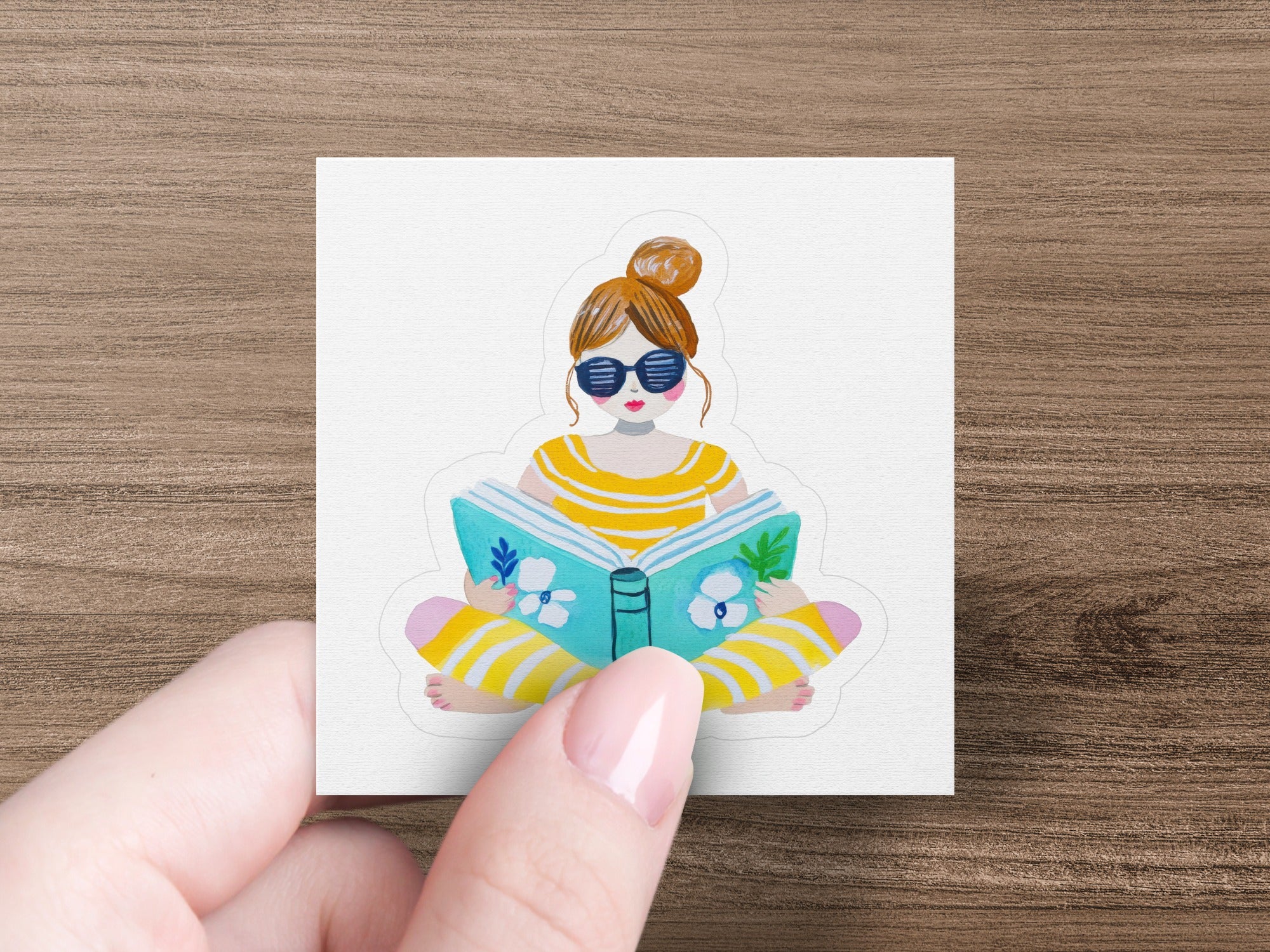 Woman wearing sunglasses reads a striped book.