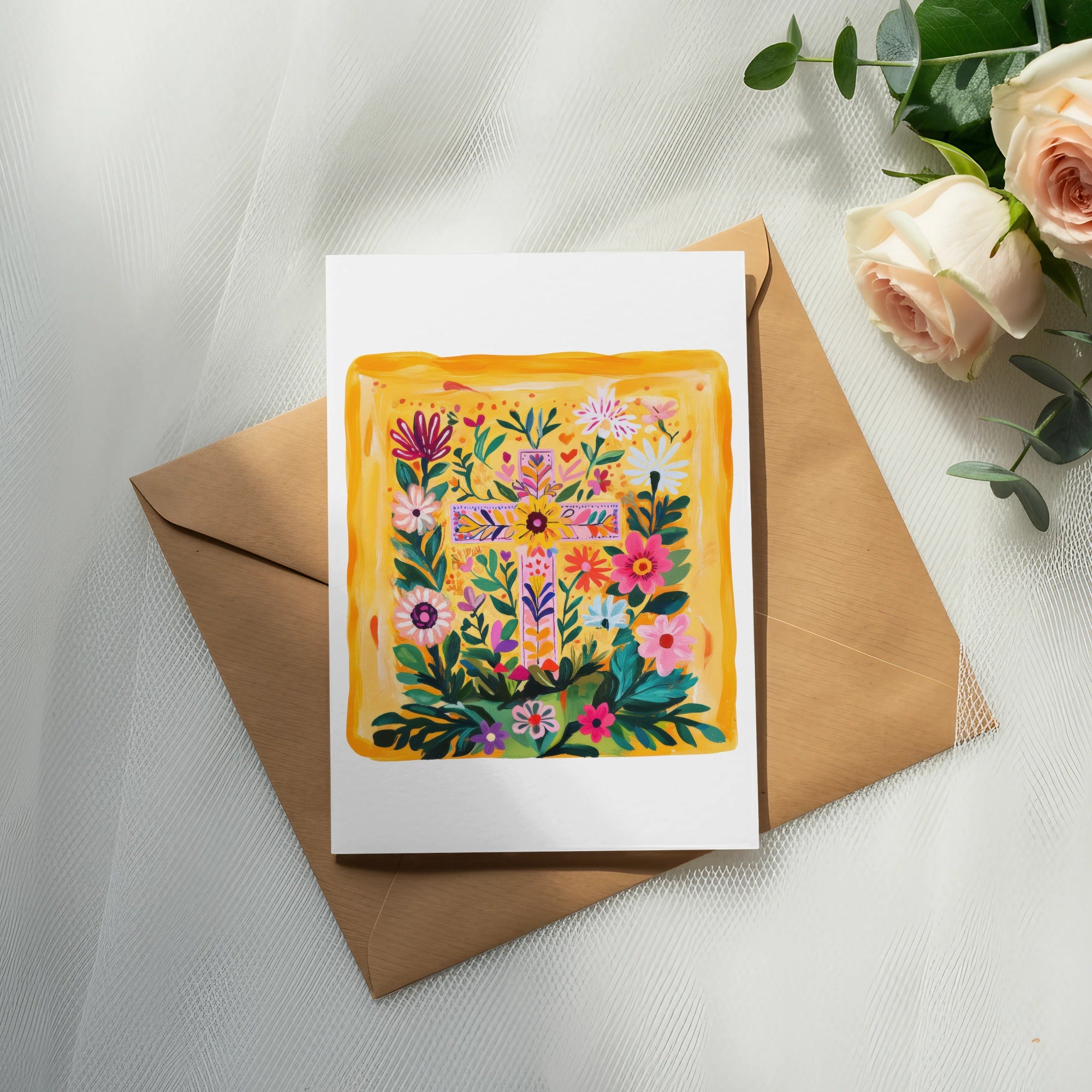 Floral cross design on a white card atop a brown envelope with roses.